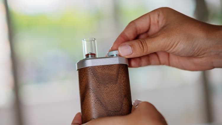 A wood-bodied portable vaporizer being tested in soft window light