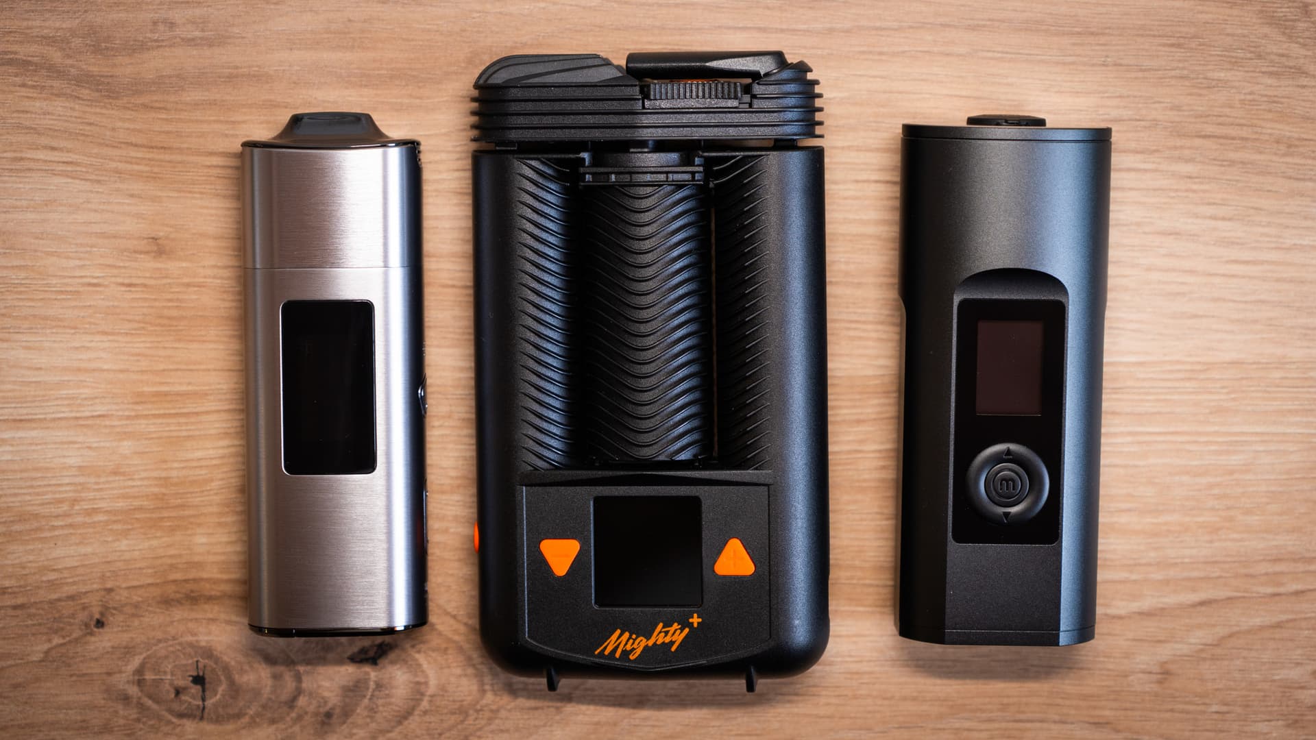 XLUX Roffu, Storz & Bickel Mighty+ and Arizer Solo 2 Max portable vaporizers laid out side by side on a wooden surface