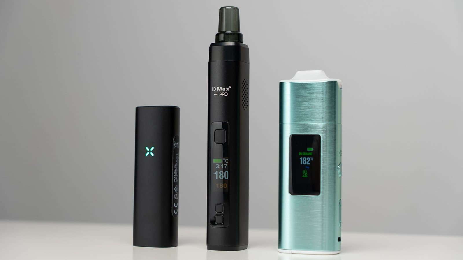 PAX Mini 2 neben XMax V4 Pro und einem petrolfarbenen Konkurrenten, Displays leuchten