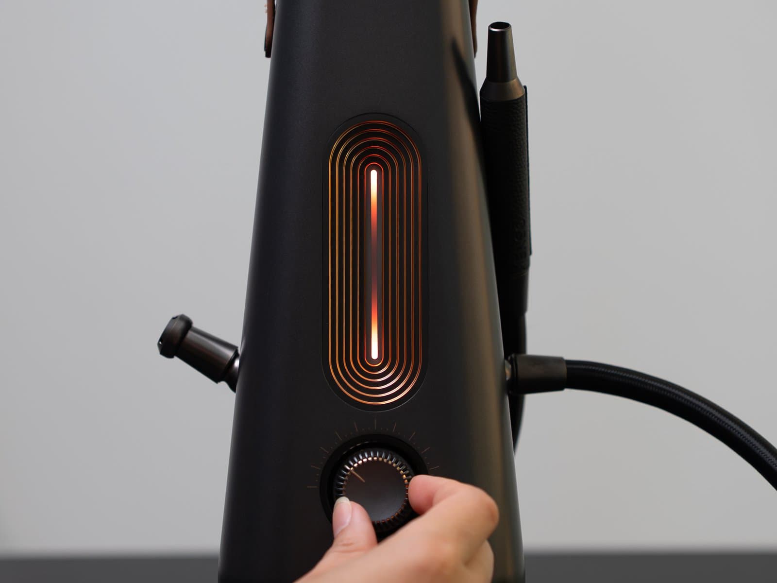 LED-Leiste des AirVape Enso leuchtet vollständig bernsteinfarben, während eine Hand das Thermodial-Stellrad mit seinen Klick-Markierungen greift