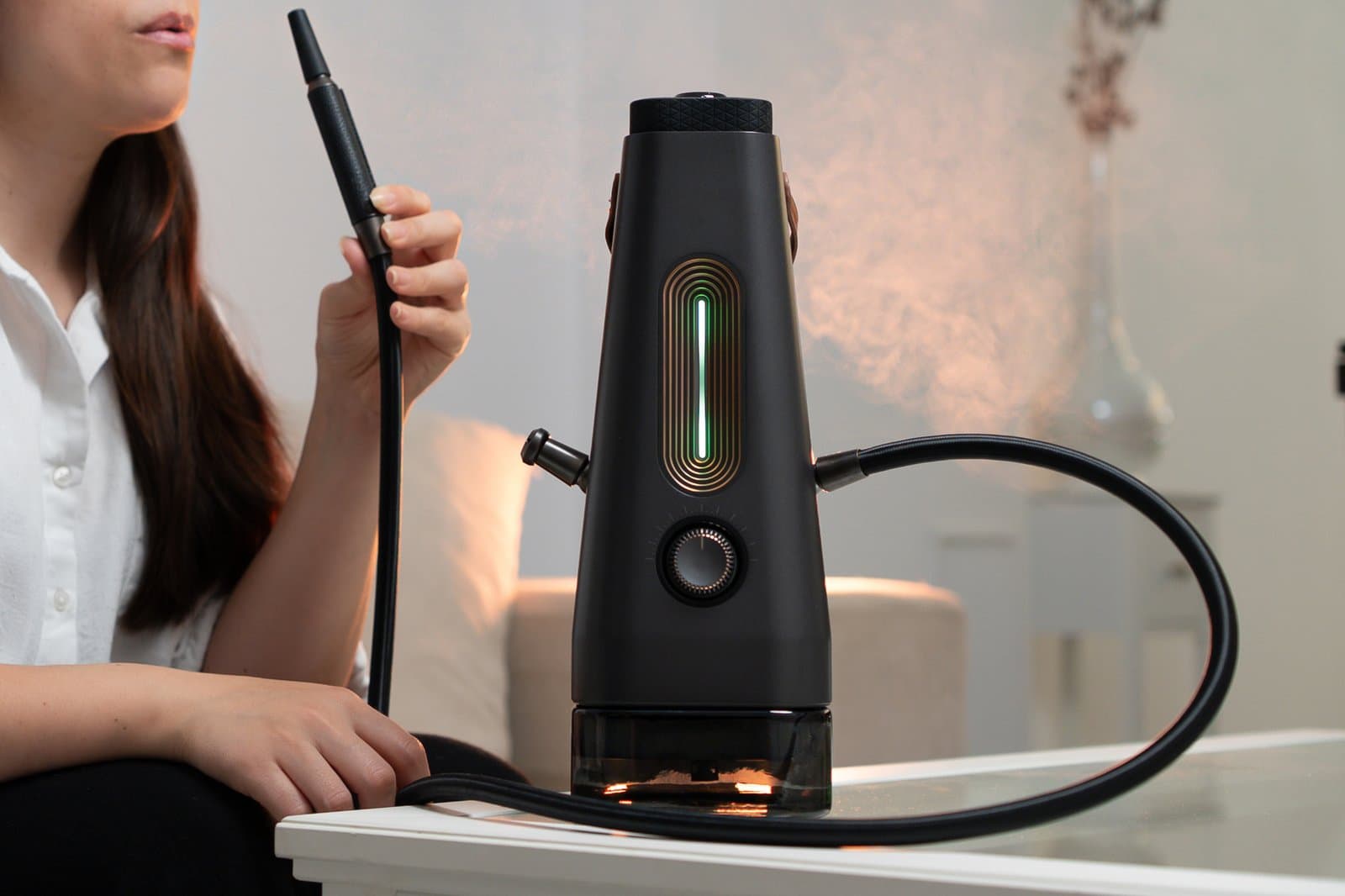 AirVape Enso mit grün leuchtender Lichtleiste, während eine Frau das Schlauch-Mundstück hält