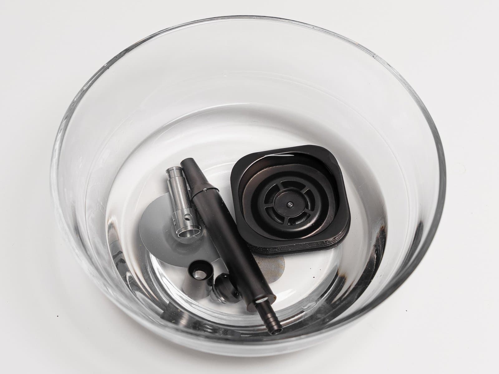 Thermocap, Mundstück, Tauchrohr und Ventilteile des AirVape Enso weichen in einer Schale mit Wasser ein