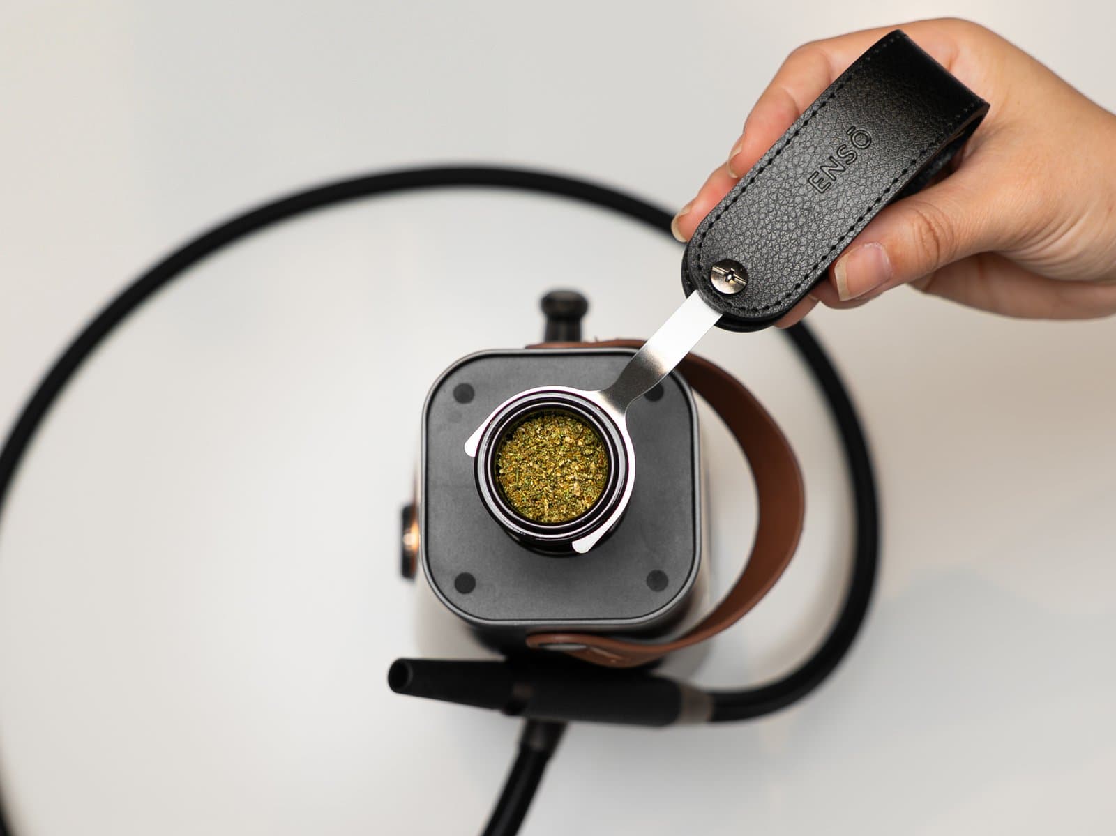 Draufsicht auf die Kammer des AirVape Enso mit einer befüllten Schale auf dem Keramikheizer, gehalten vom Schalen-Werkzeug, Thermocap abgenommen