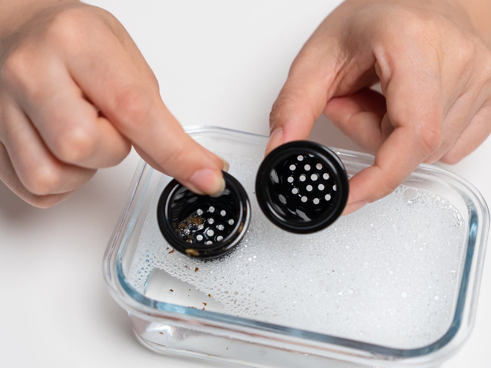 Two AirVape Enso ceramic cups with residue held over a dish of soapy water