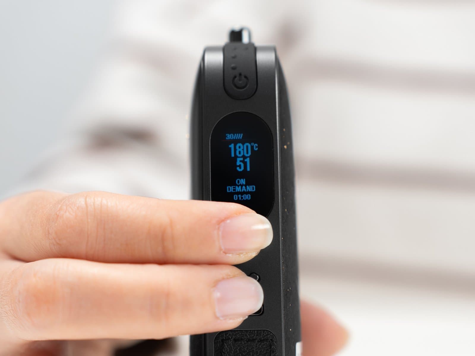 Display des AirVape Legacy Pro 2 im On-Demand-Modus, ein Finger auf den Temperaturtasten