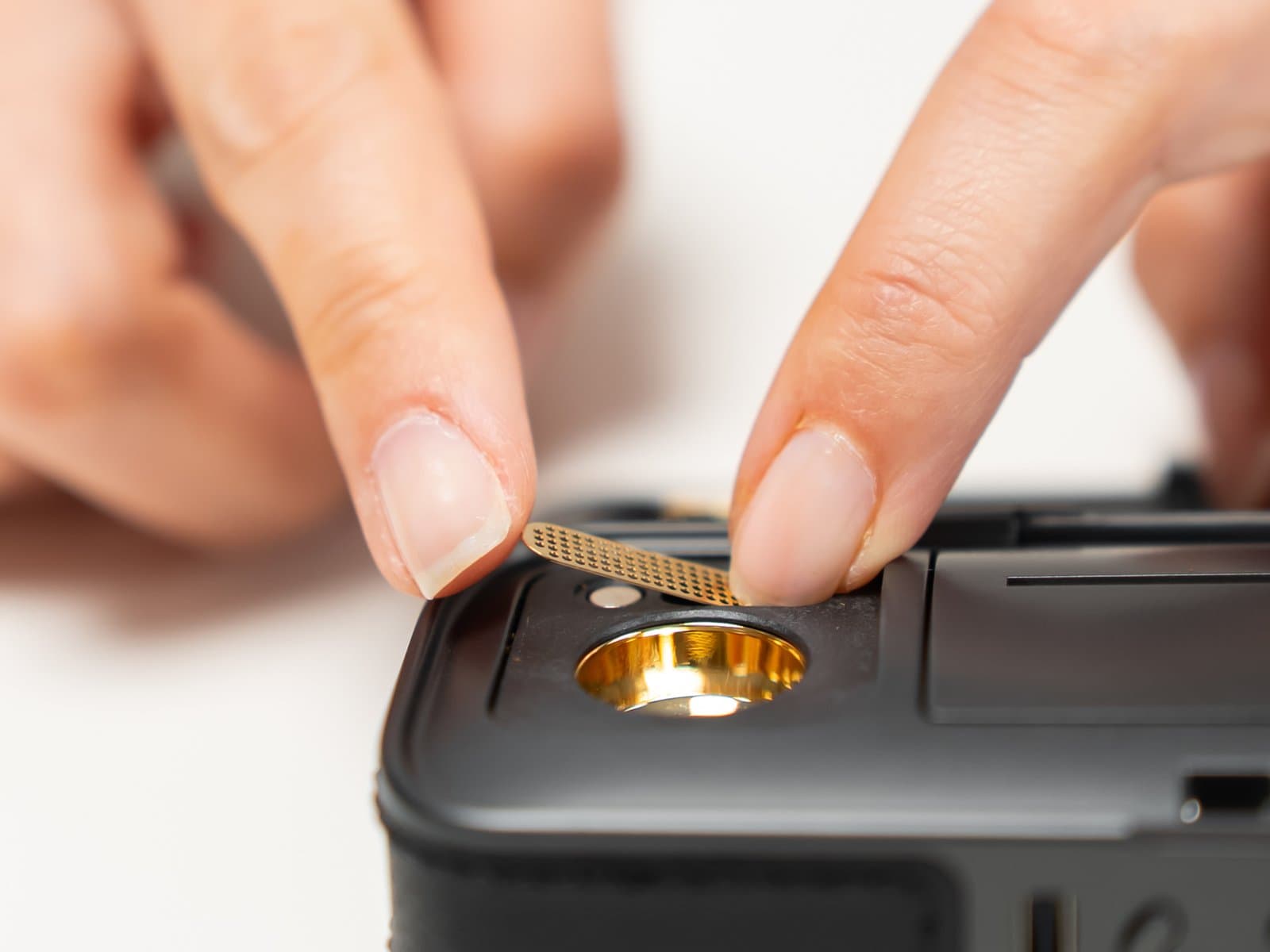 Fingers lifting magnetic screen off gold chamber of Legacy Pro 2