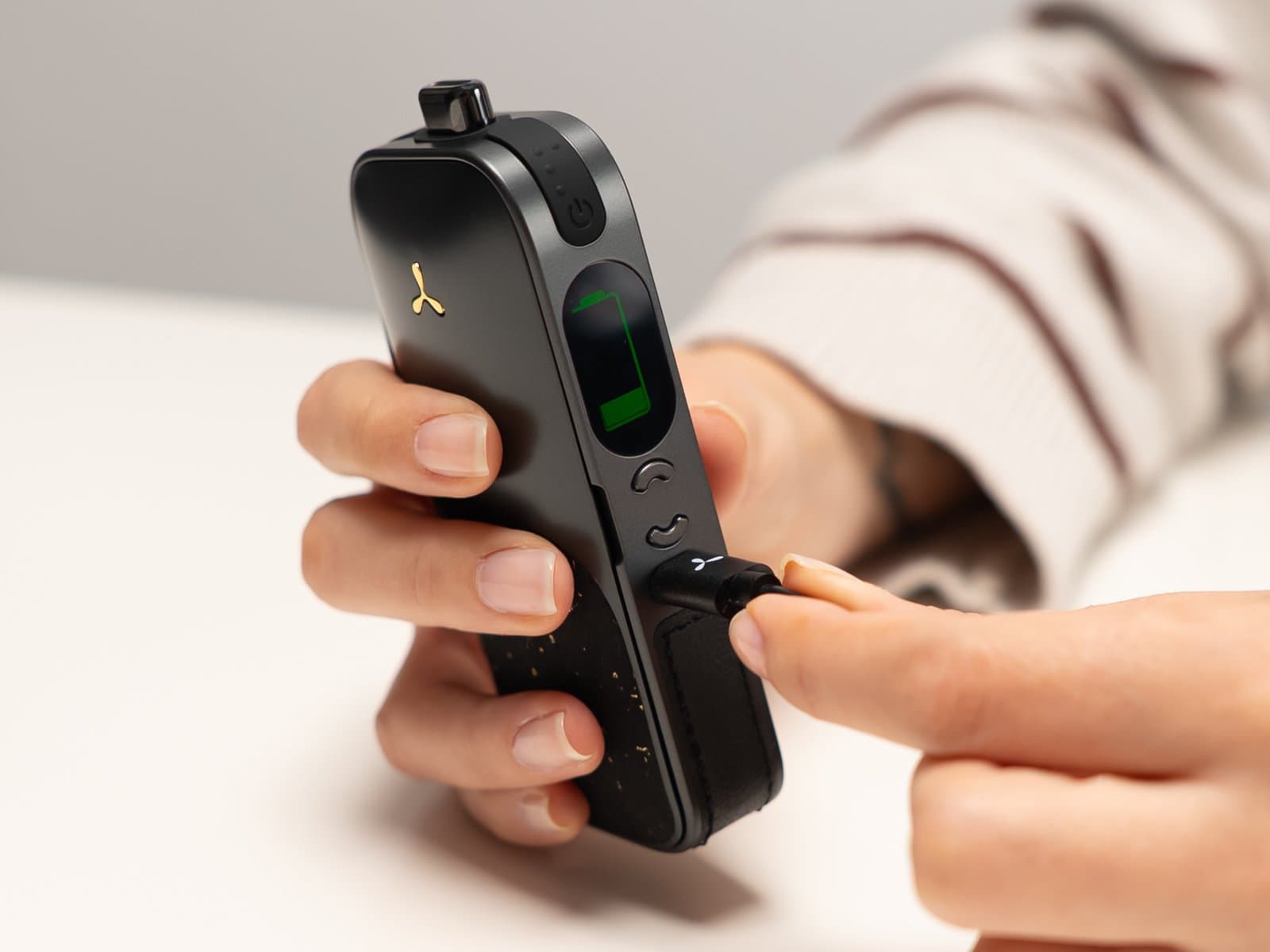 Hands plugging USB-C into AirVape Legacy Pro 2, green battery icon on screen