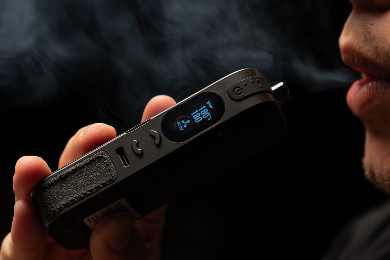 Man exhaling vapor cloud from AirVape Legacy Pro 2 against dark background
