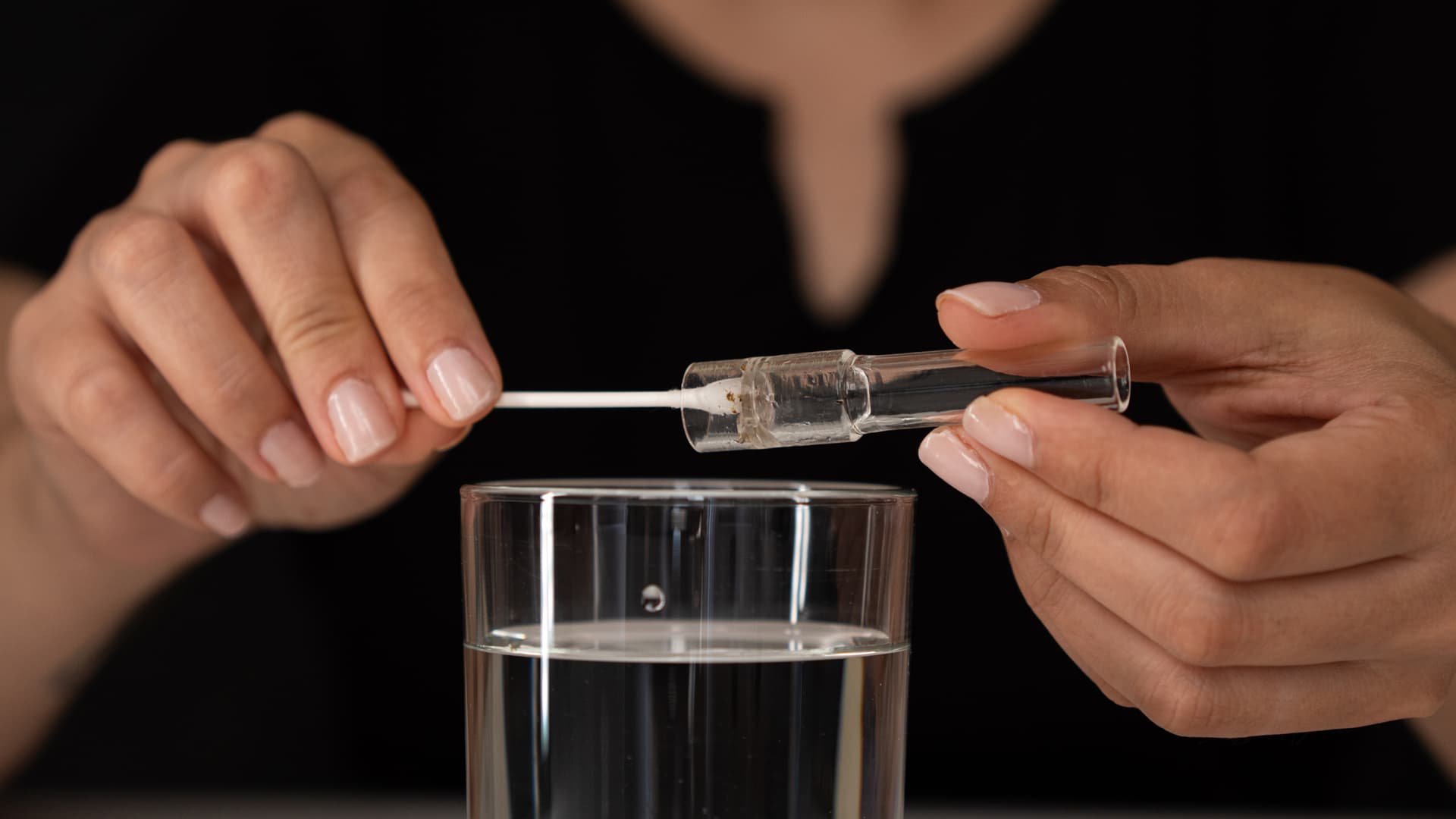 Der Glas-Stem wird über einem Glas mit Flüssigkeit mit einem Wattestäbchen gereinigt