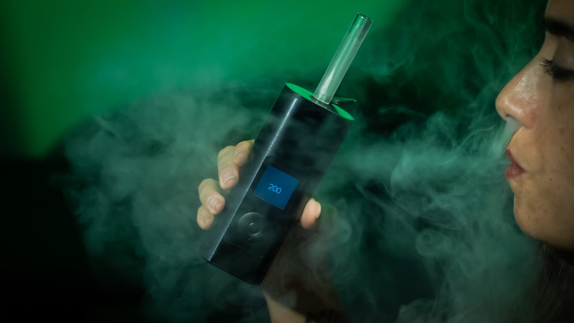 Arizer Solo 3 in use with the borosilicate glass stem catching warm light, faint vapor visible in the airpath