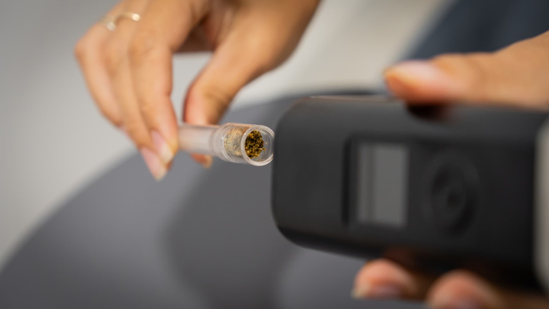 Borosilicate glass aroma tube being removed from the Arizer Solo 3 after a session, with vaped brown herb clearly visible through the transparent glass bowl