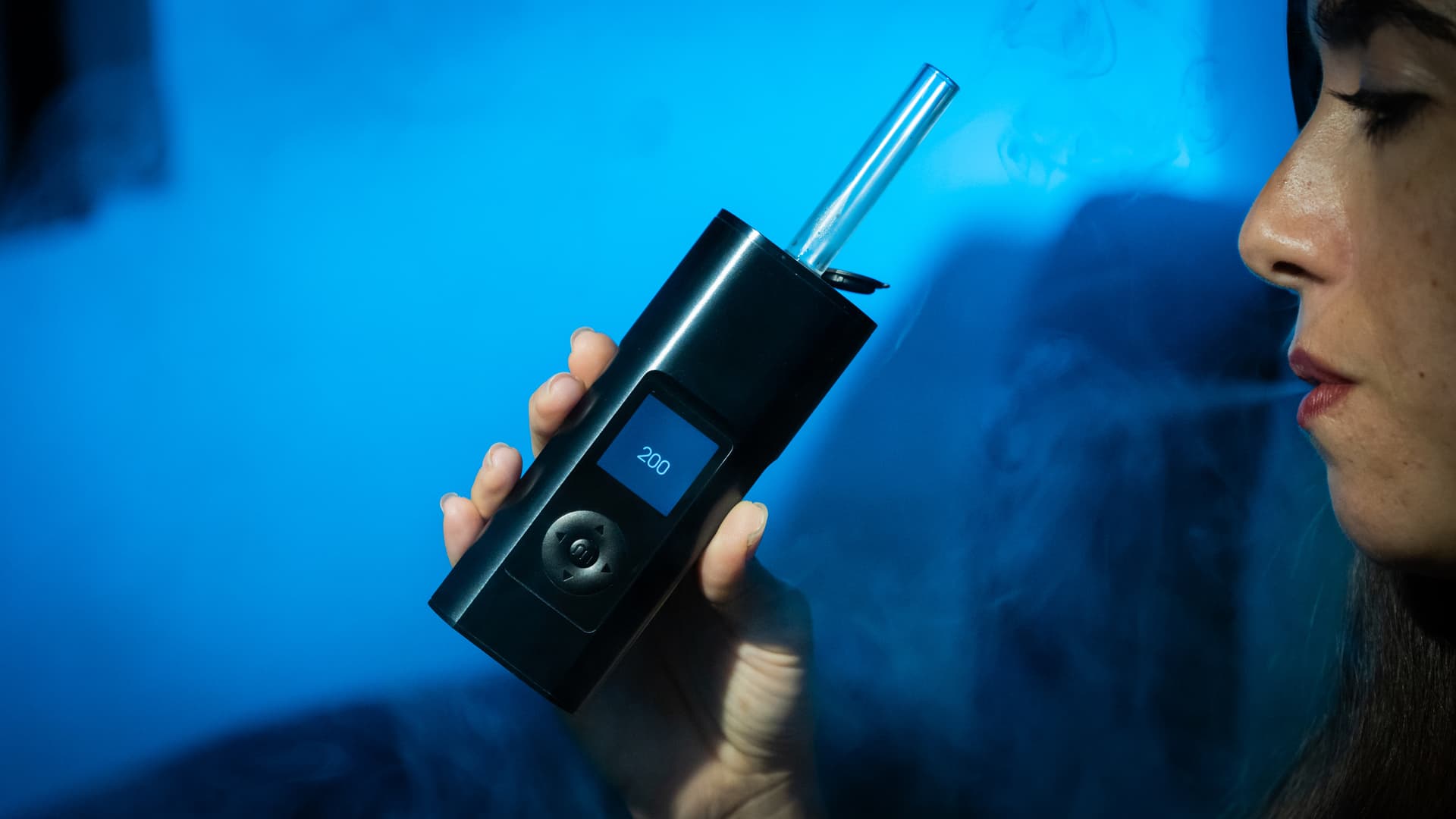 Ausatmen von Dampf mit dem Solo 3 in der Hand unter blauem Licht