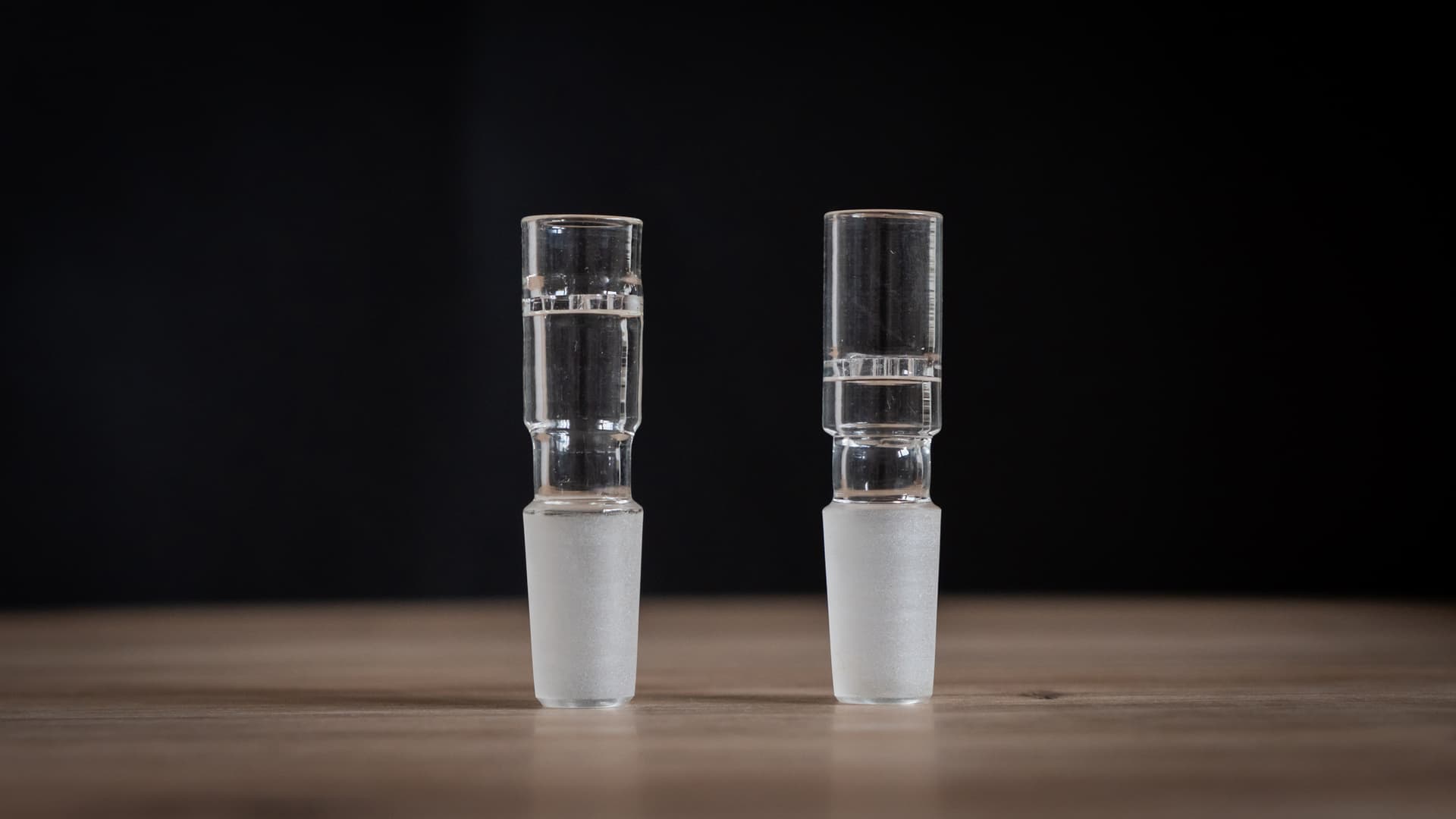 A glass water pipe adapter showing the frosted ground-glass 14mm male joint on one end and the open mouthpiece end on the other