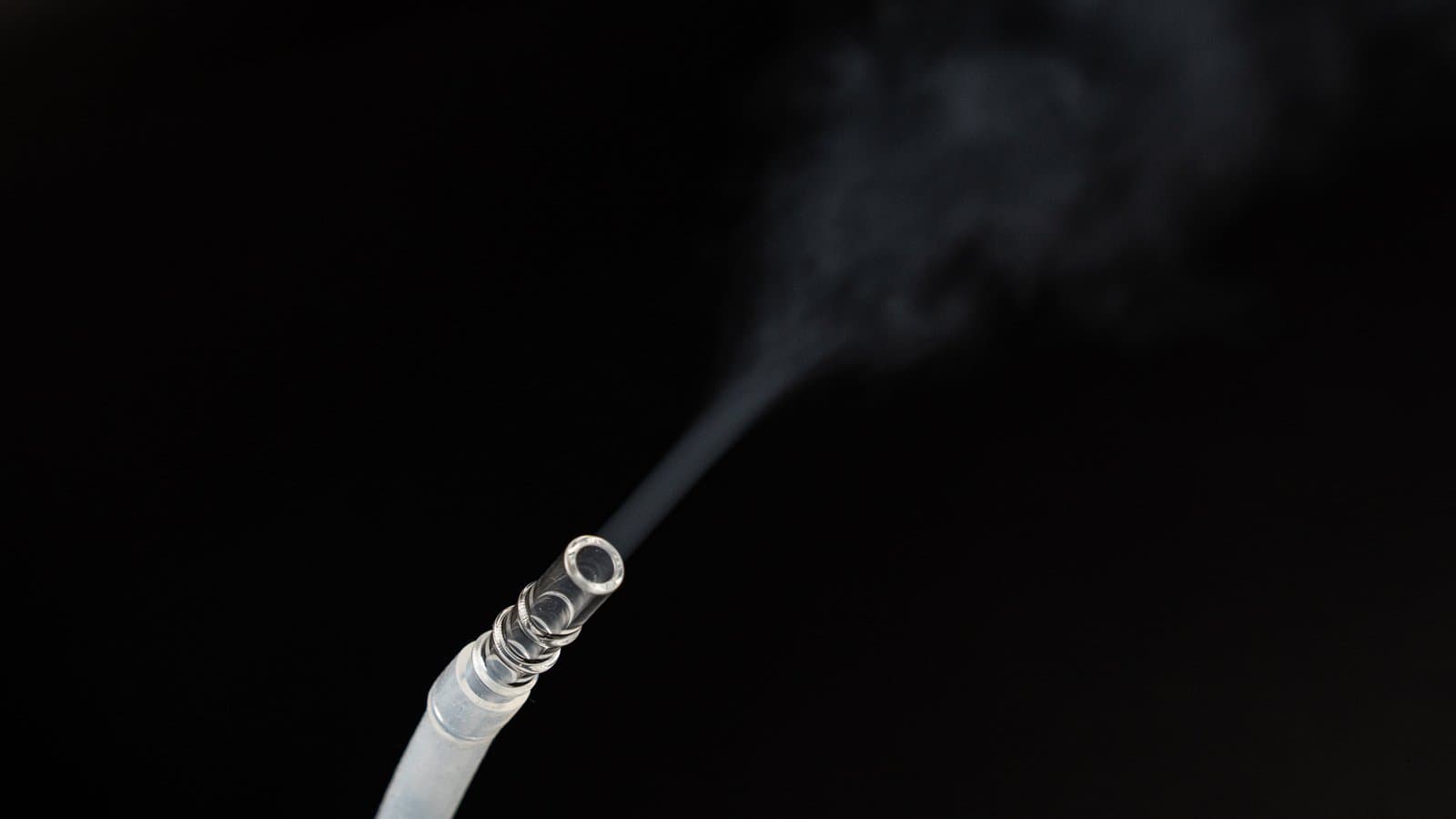 Dense vapor streaming from glass whip mouthpiece on black