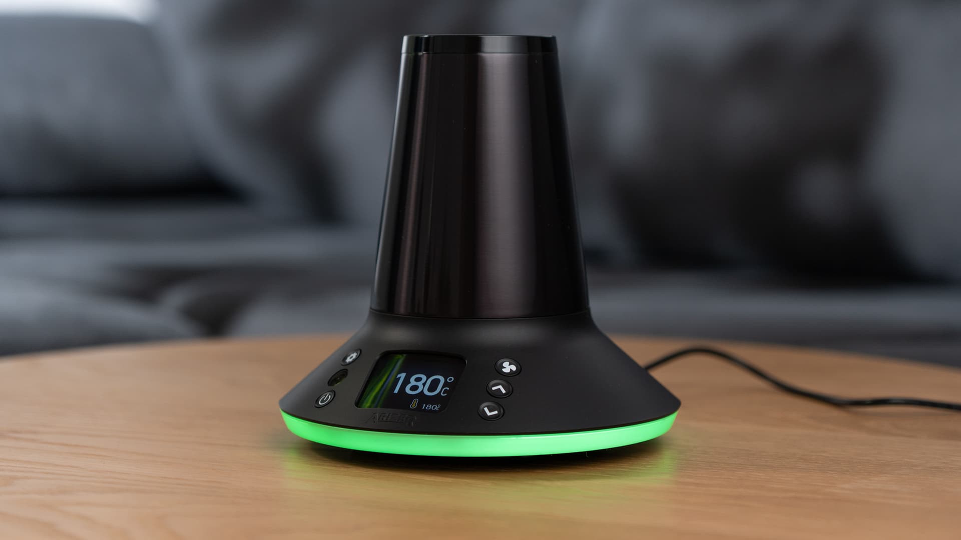 Arizer XQ2 powered on at 180°C with green LED ring glowing on coffee table
