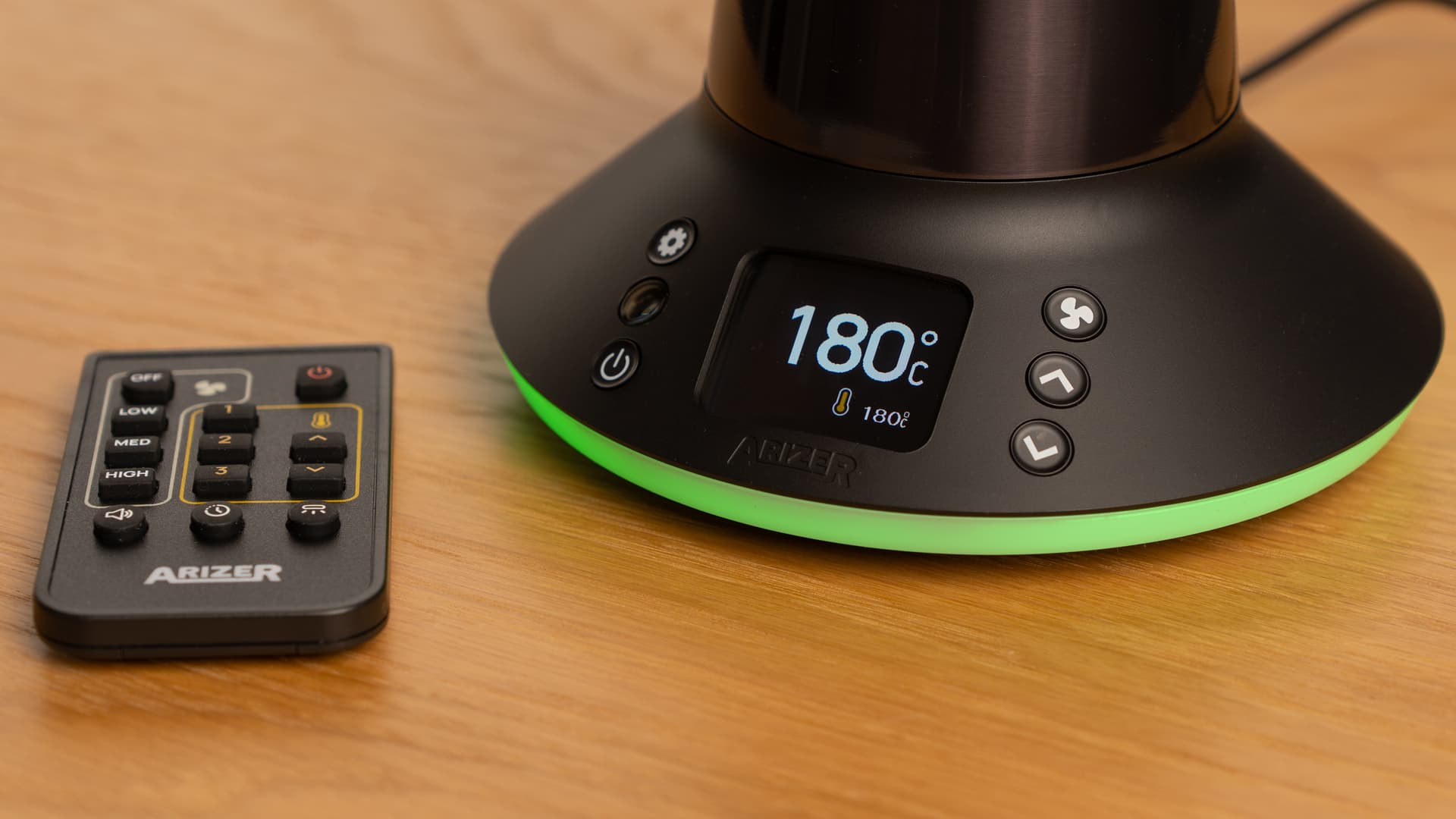 Arizer XQ2 infrared remote control next to base unit displaying 180°C with green LED ring