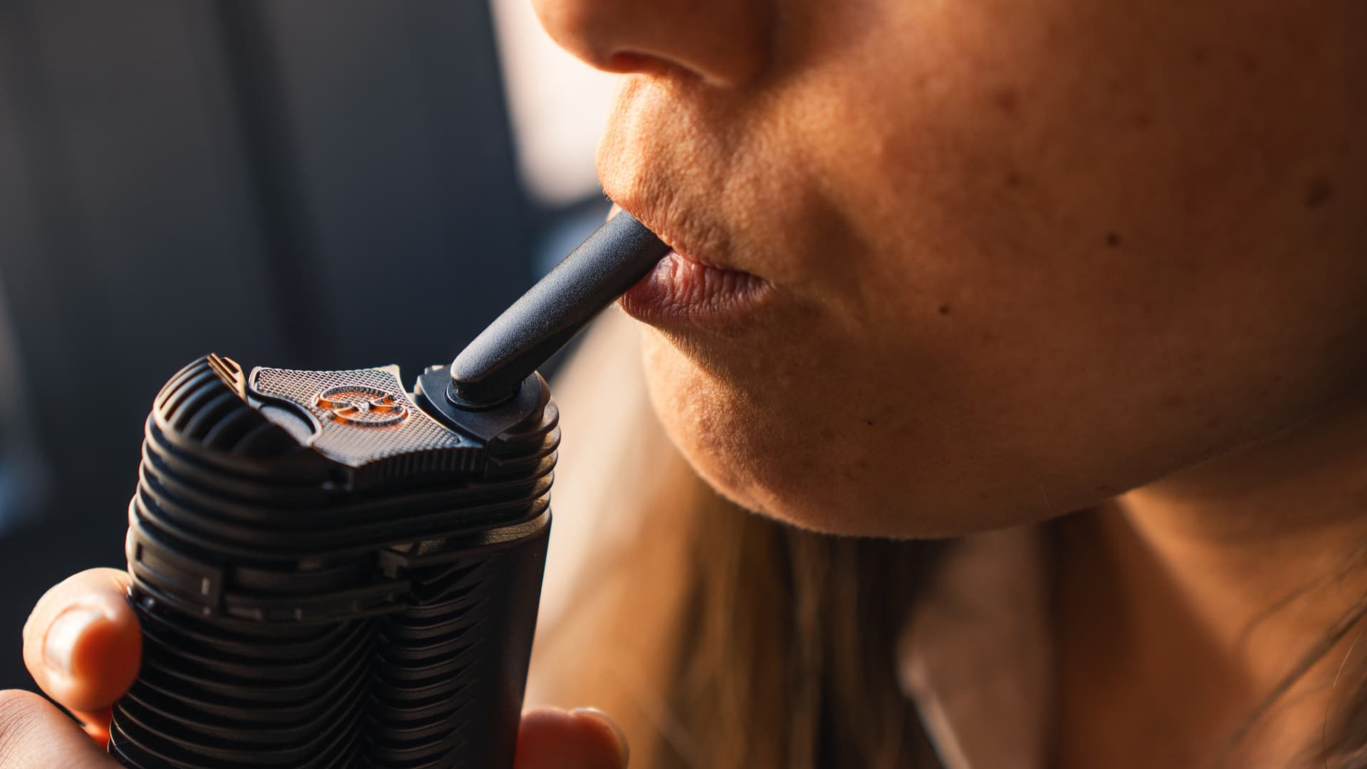 Nahaufnahme einer Hand, die einen tragbaren Vaporizer ruhig und kontrolliert an die Lippen hält