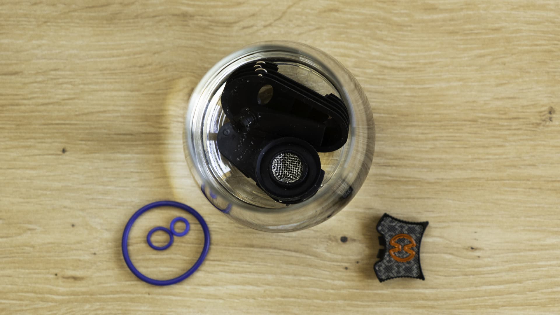 Vaporizer parts submerged in a clear glass dish of isopropyl alcohol with visible resin dissolving into the liquid