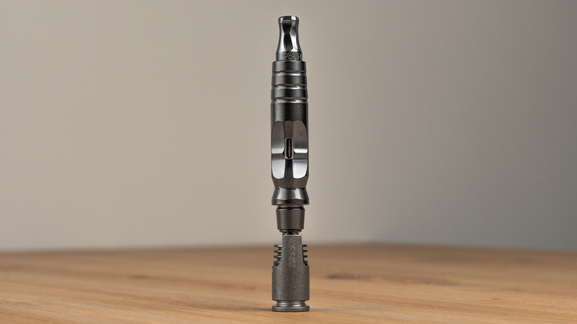 A DynaVap HyperDyn showing the machined titanium body with built-in 10mm and 14mm water pipe tapers, photographed on a dark stone surface