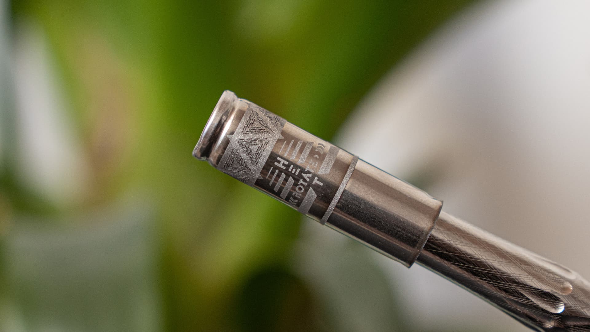 Close-up of DynaVap UniDyn BallR Cap showing engraved H and T heat position indicators and DynaVap logo on titanium body