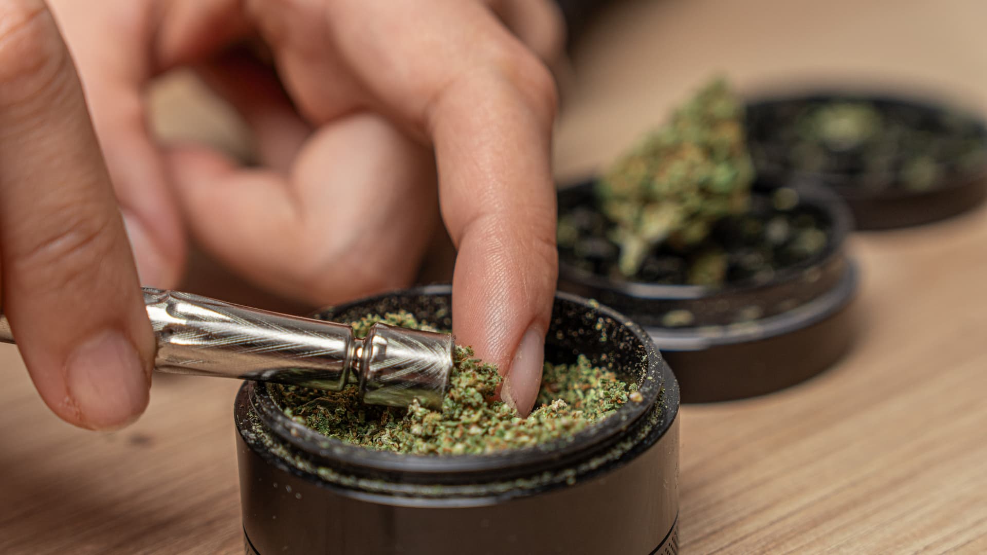 Hände befüllen die Spitze des DynaVap UniDyn direkt aus einem Grinder voll mit gemahlenem Cannabis