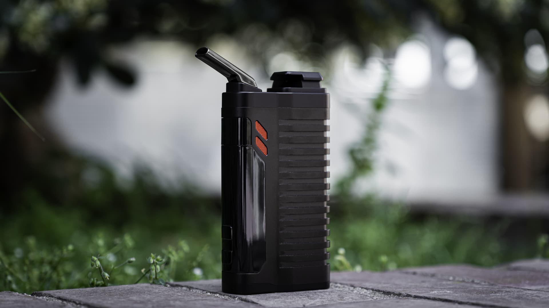 The Fenix 2 MAX vaporizer photographed on a stone surface, ribbed black body with orange accent ring visible