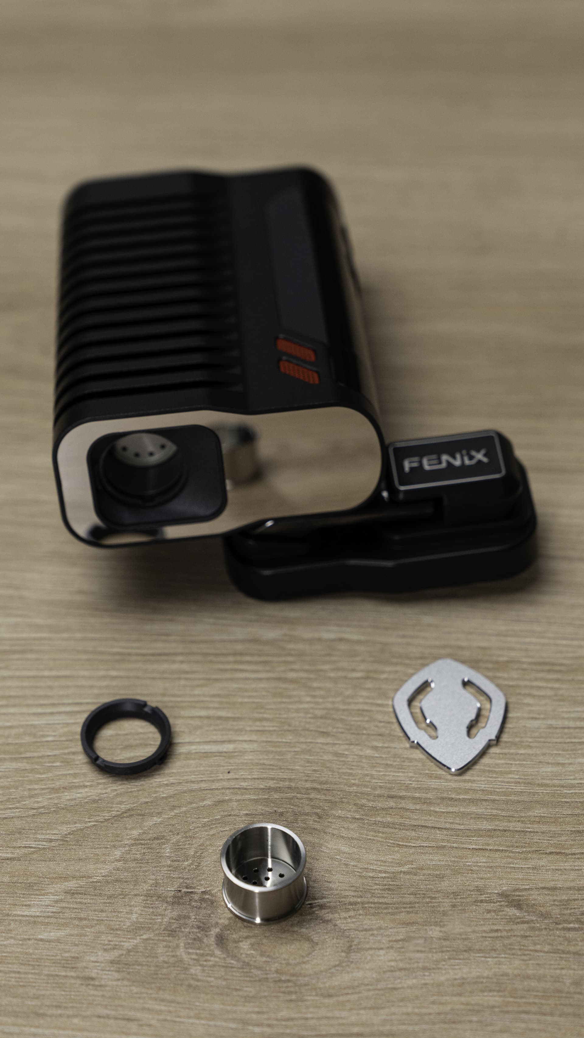 Fenix 2 MAX disassembled with titanium chamber, O-ring, and removal tool laid out on a wooden surface