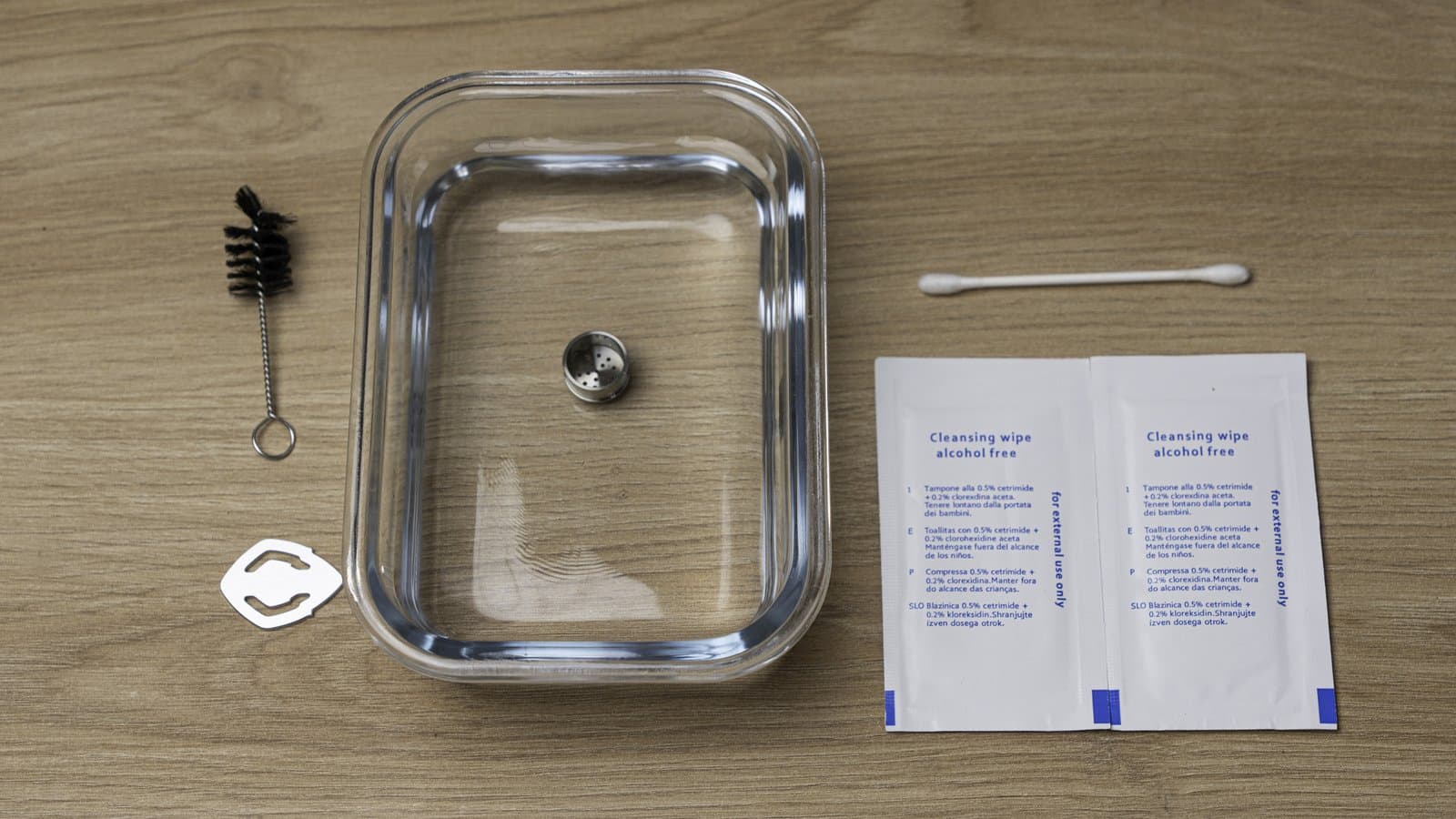 Fenix 2 MAX chamber in a glass dish beside the brush, removal tool, a cotton swab and cleansing wipes