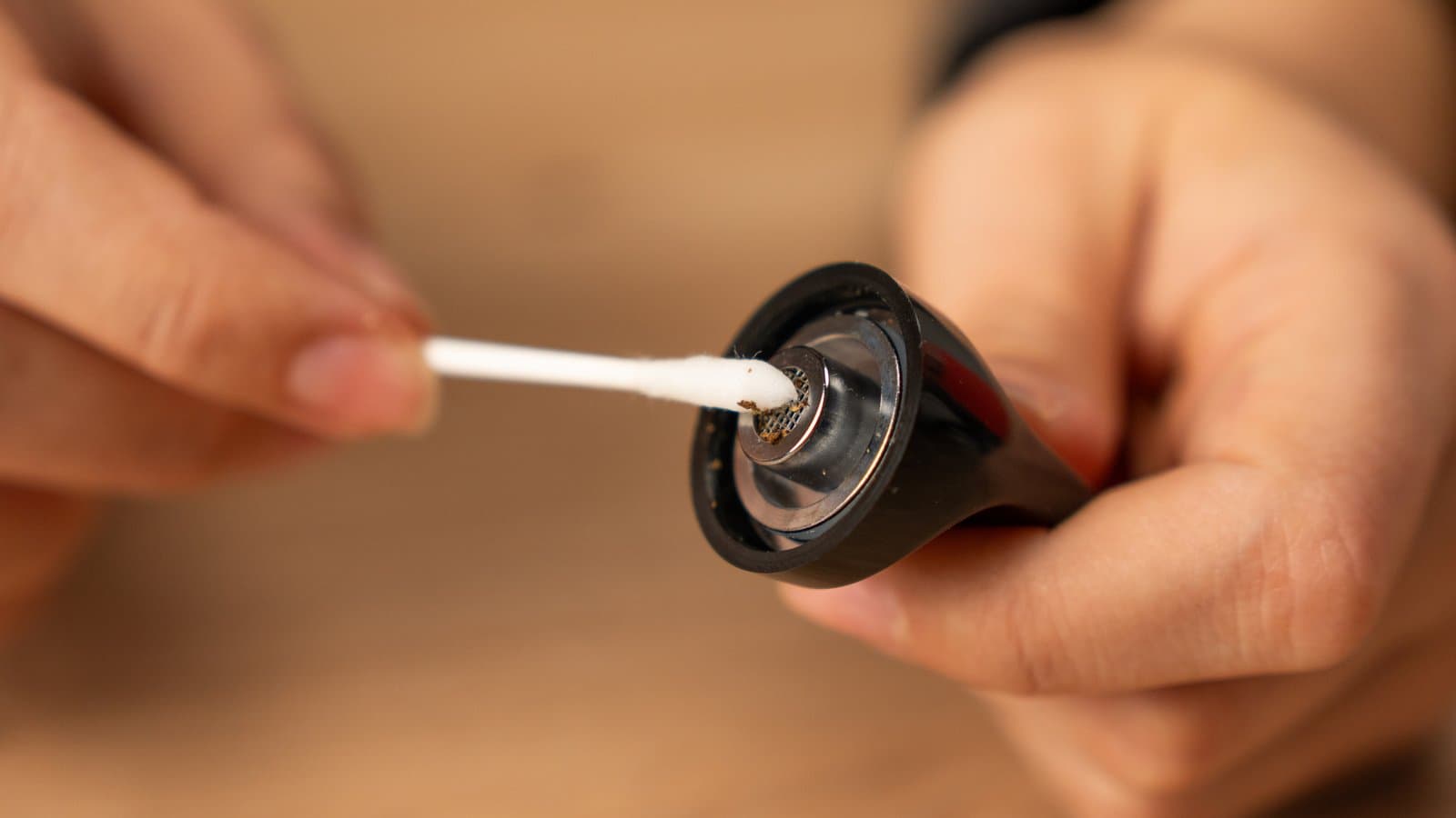 Cotton swab cleaning the screen inside the detached Flowermate Aura mouthpiece