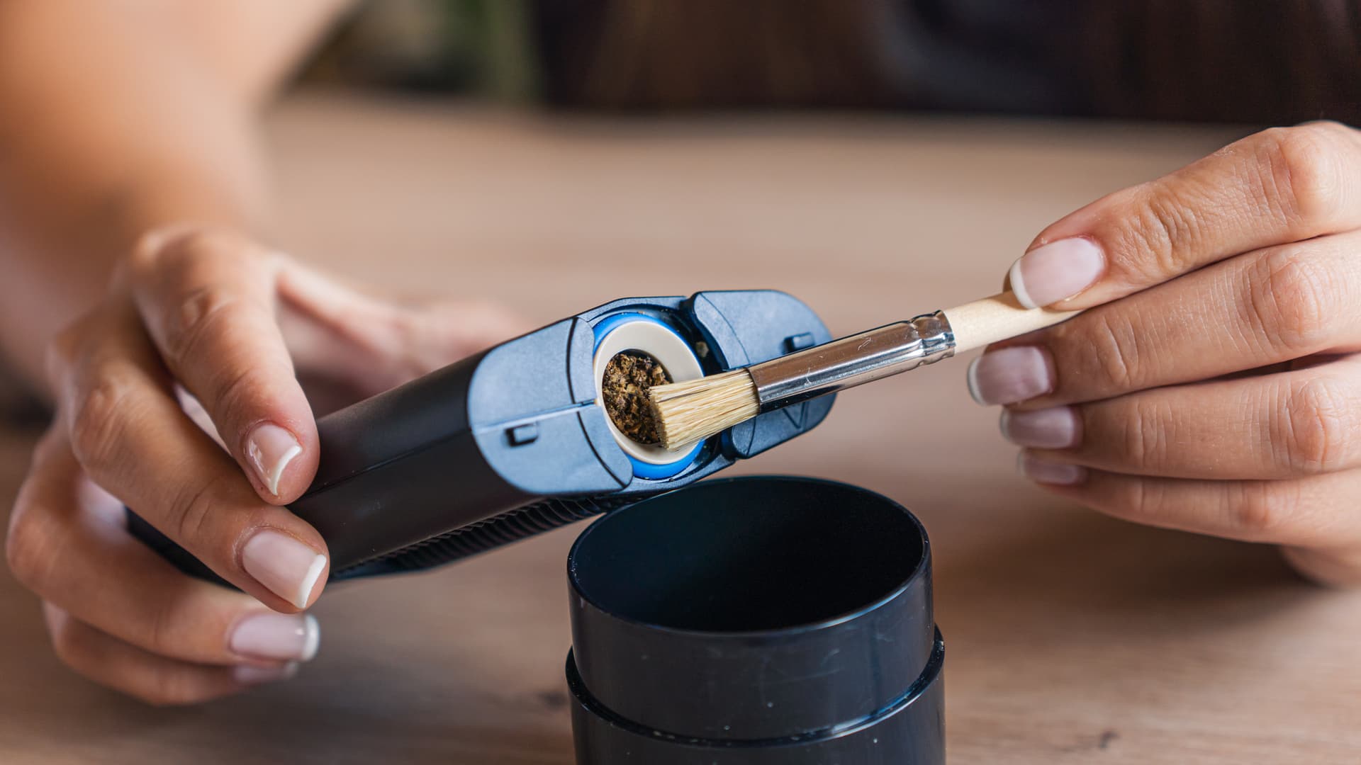 A small cleaning brush removing dark resin buildup from the inside of a portable vaporizer oven