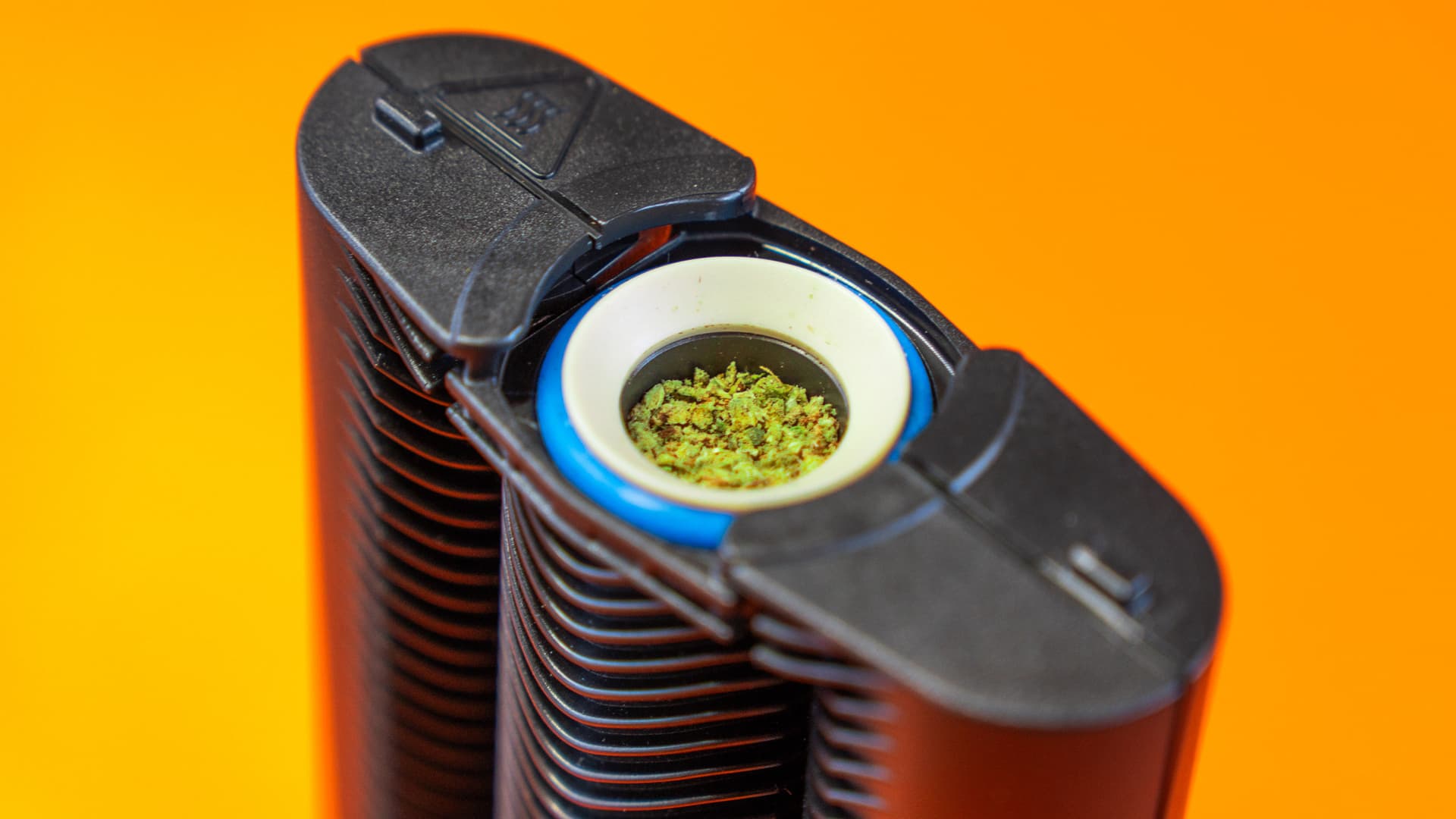 The Mighty+ vaporizer with its hybrid heating chamber visible and loaded with ground cannabis, photographed under warm directional light