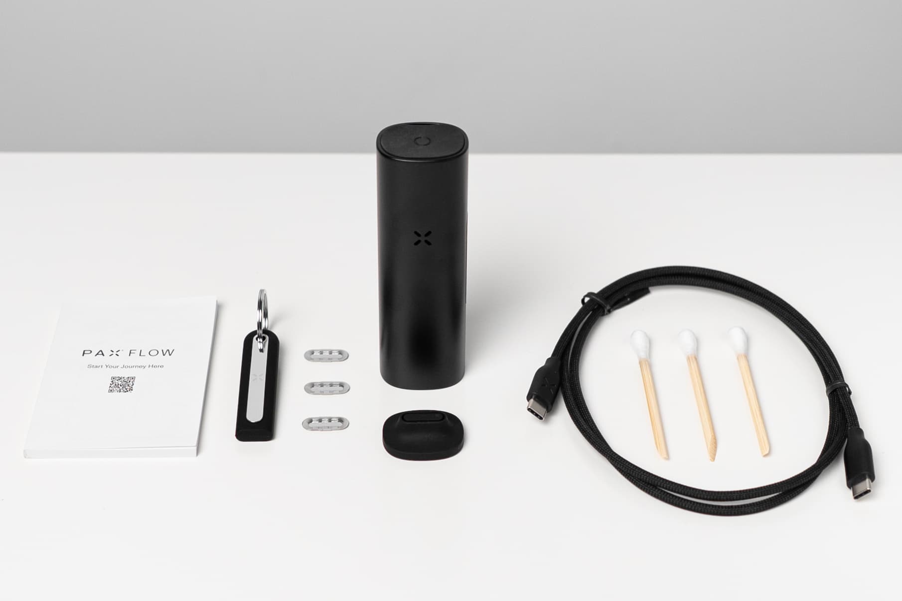 Flatlay des PAX Flow Kit-Inhalts mit Vaporizer, Schnellstartanleitung, Sieben, USB-C-Kabel und Wattestäbchen