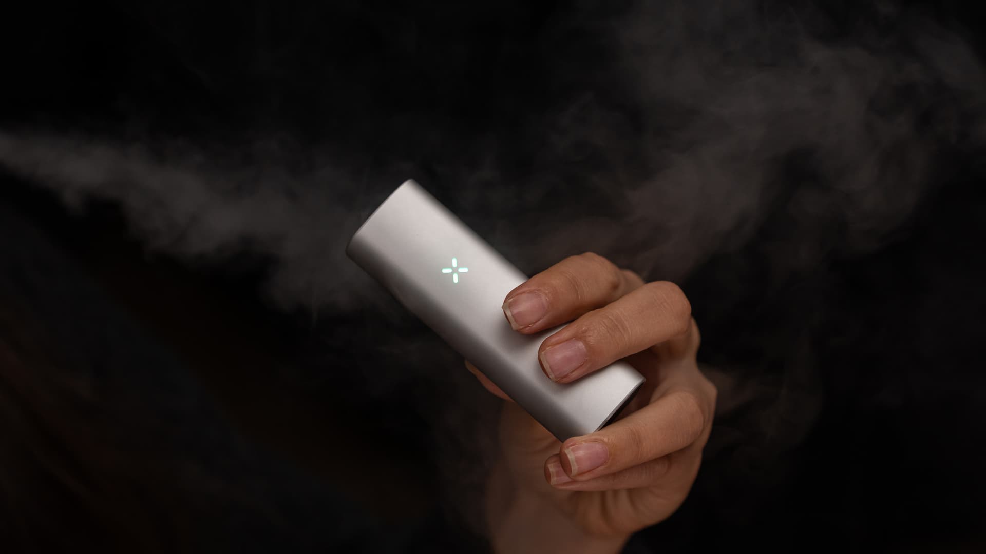 PAX Mini with its LED ring illuminated, vapor wisps rising from the mouthpiece