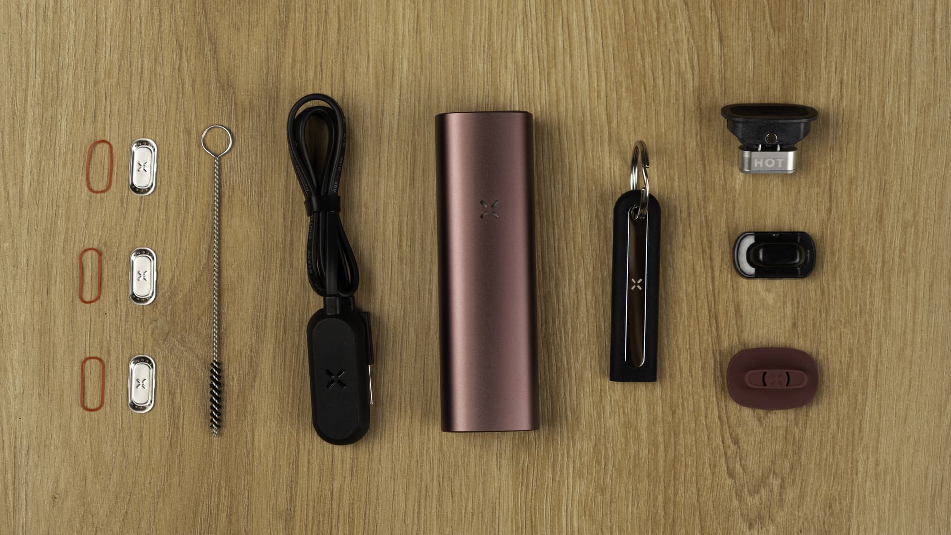 Komplettes PAX Plus Kit flach ausgelegt mit Konzentrat-Einsatz, beiden Mundstücken, Heizkammerdeckeln, Multitool, Bürste und magnetischem Ladekabel