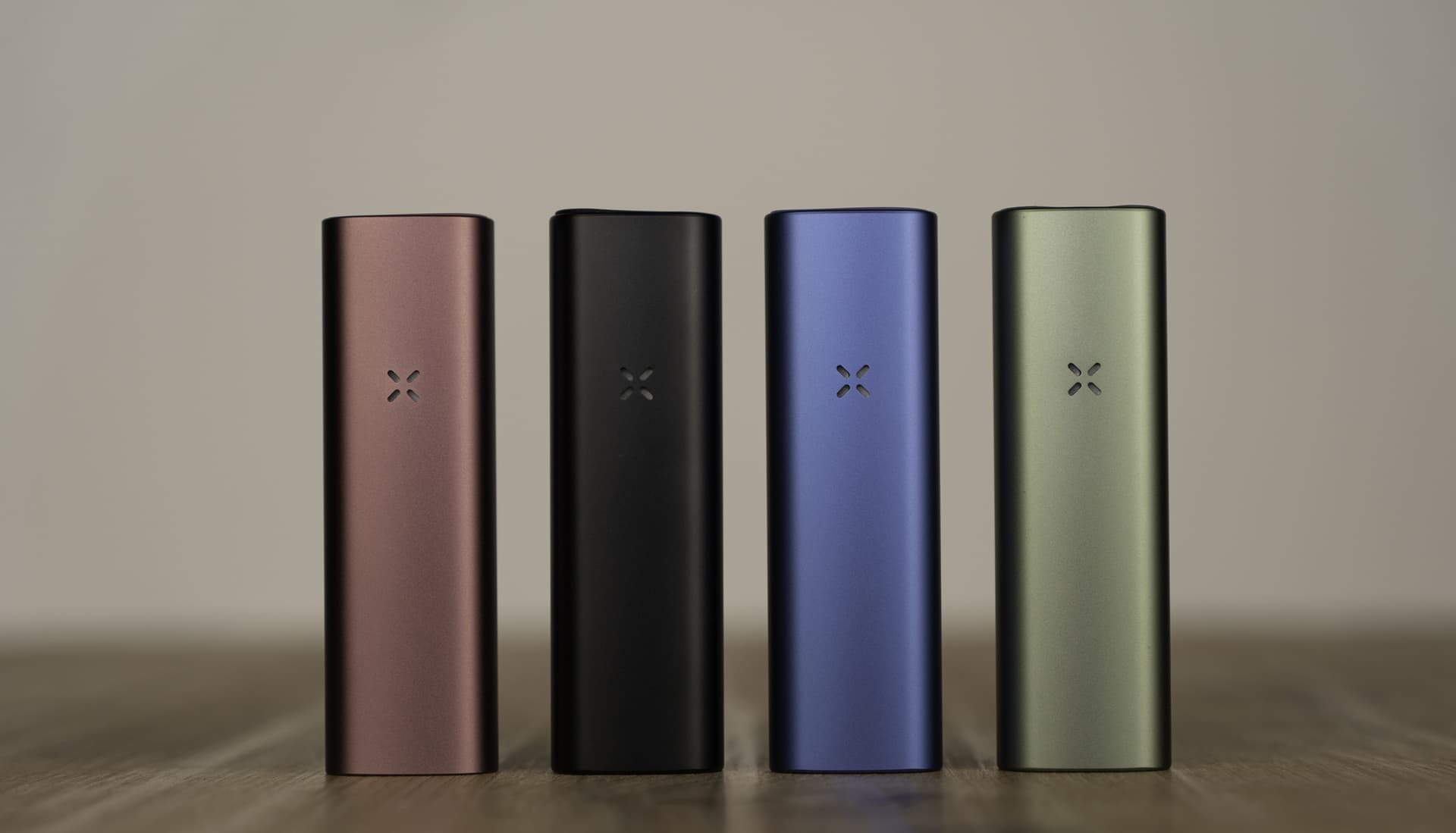 PAX Plus in Elderberry, Onyx, Periwinkle und Sage auf einem Holztisch