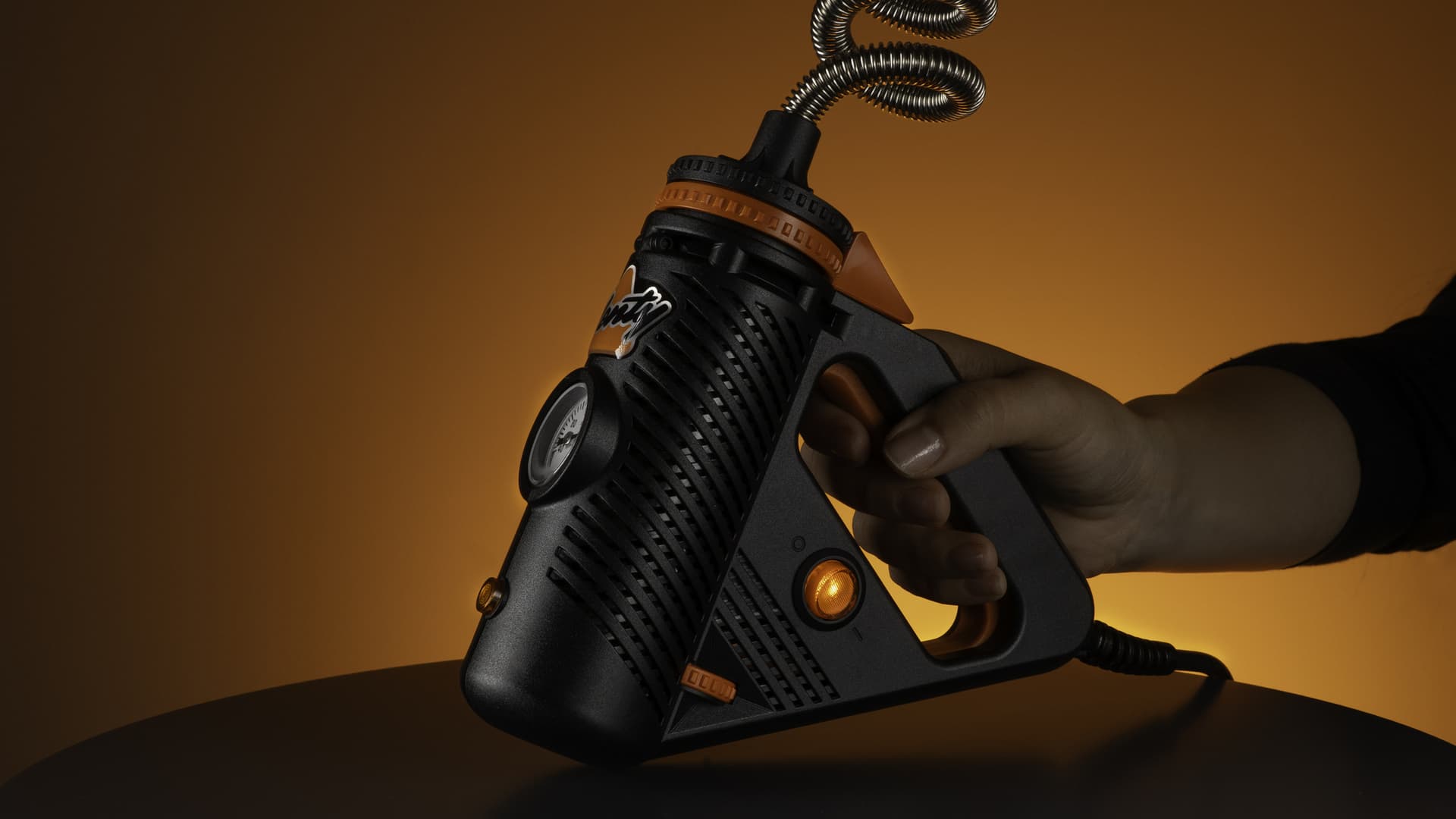 Hand squeezing Plenty vaporizer handle with power indicator light glowing orange