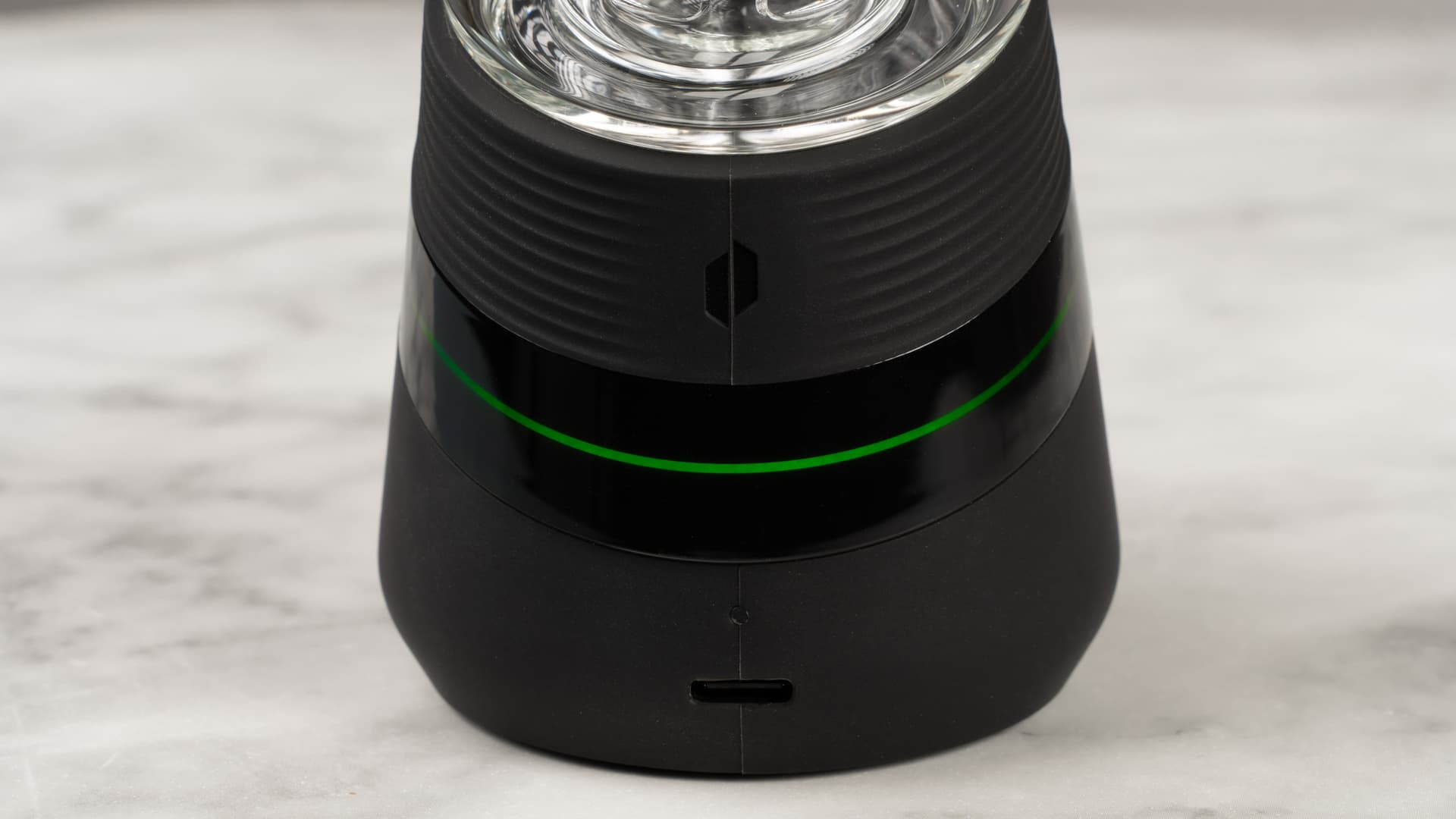 Puffco New Peak base with its light band glowing green above the USB-C port