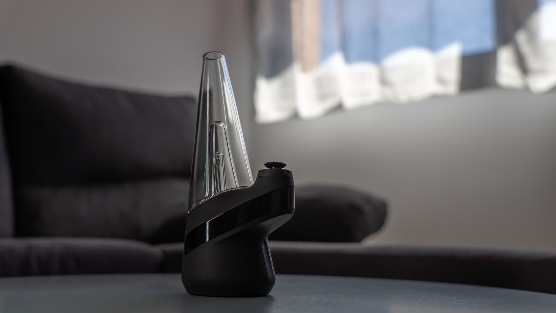 Puffco New Peak auf einem dunklen Tisch in einem gemütlichen Wohnzimmer