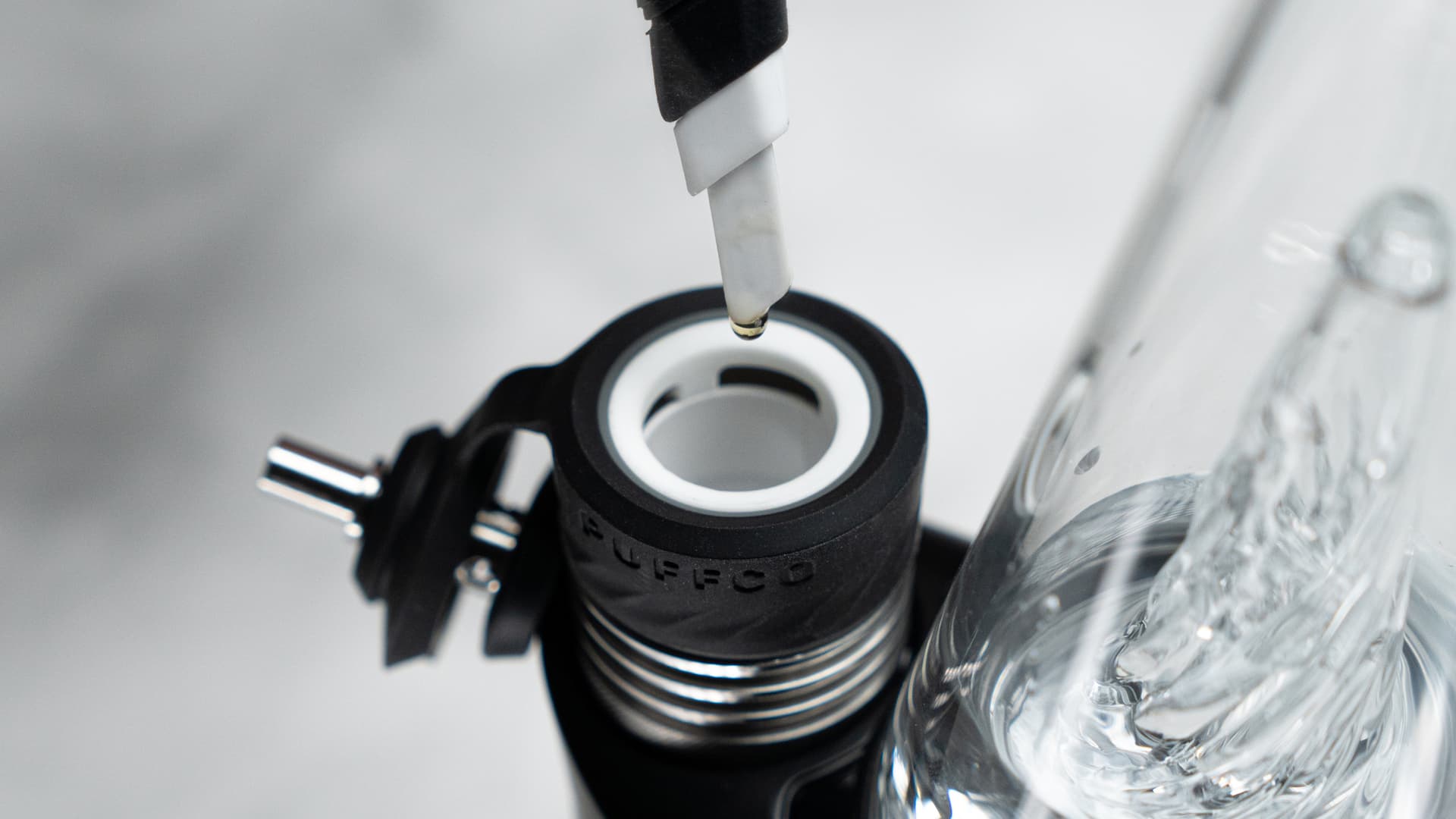 A hot knife dripping concentrate into the 3D ceramic chamber of a Puffco Peak Pro, showing the loading technique in detail