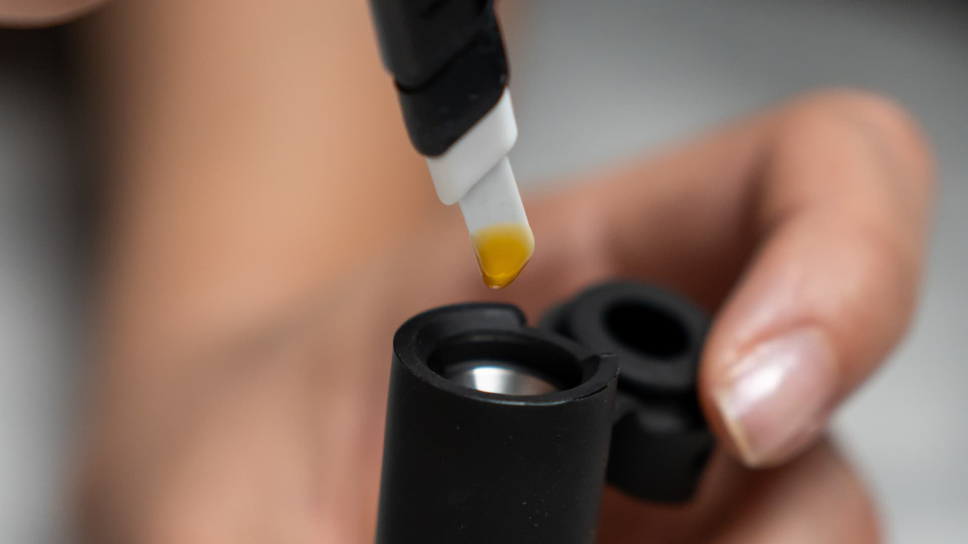 Macro close-up of amber cannabis concentrate on a heated loading tool
