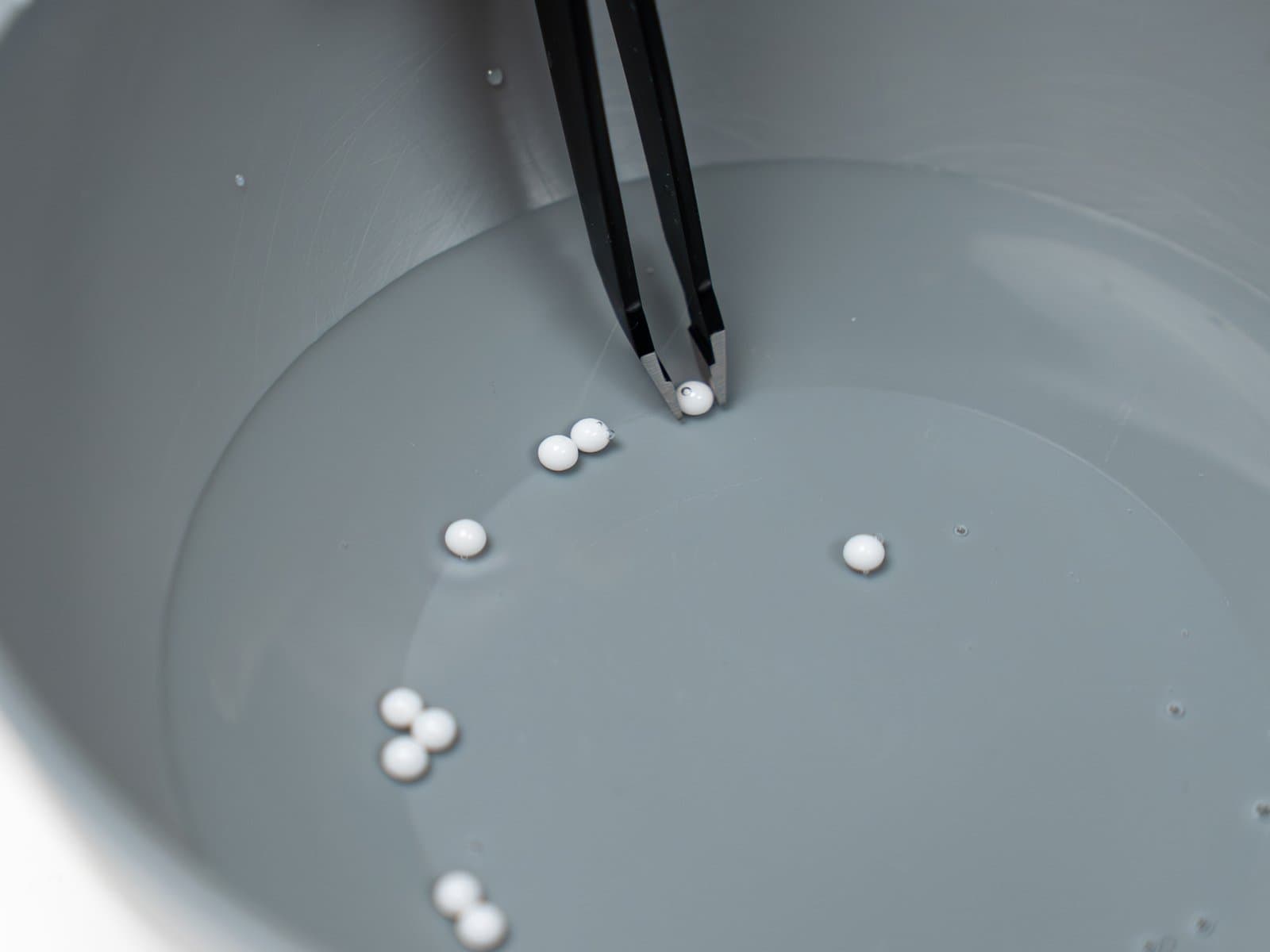 Tweezers lifting zirconia balls out of an alcohol soak