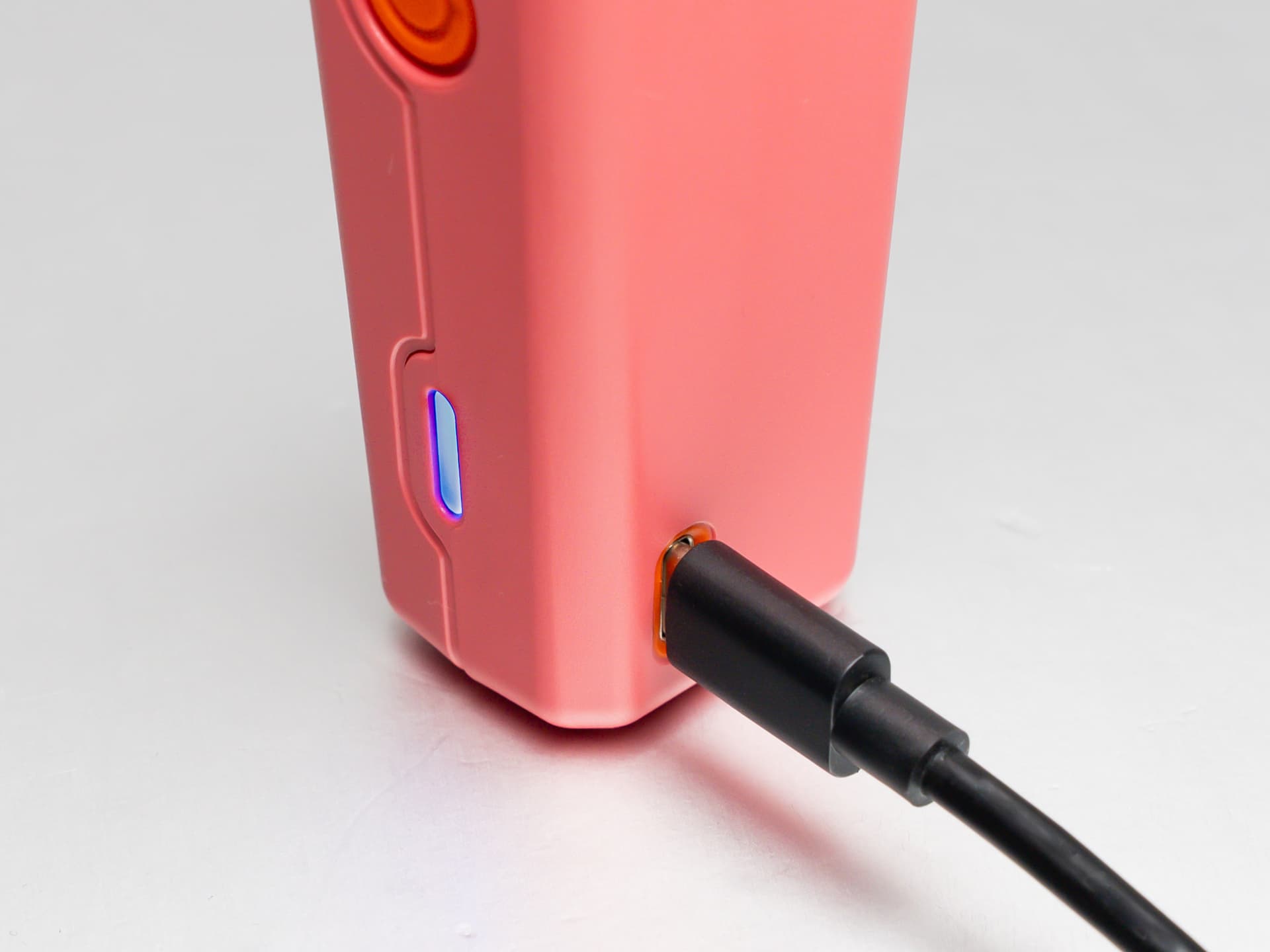 Pinker Veazy Vaporizer mit eingestecktem USB-C-Kabel und leuchtender blauer Lade-LED