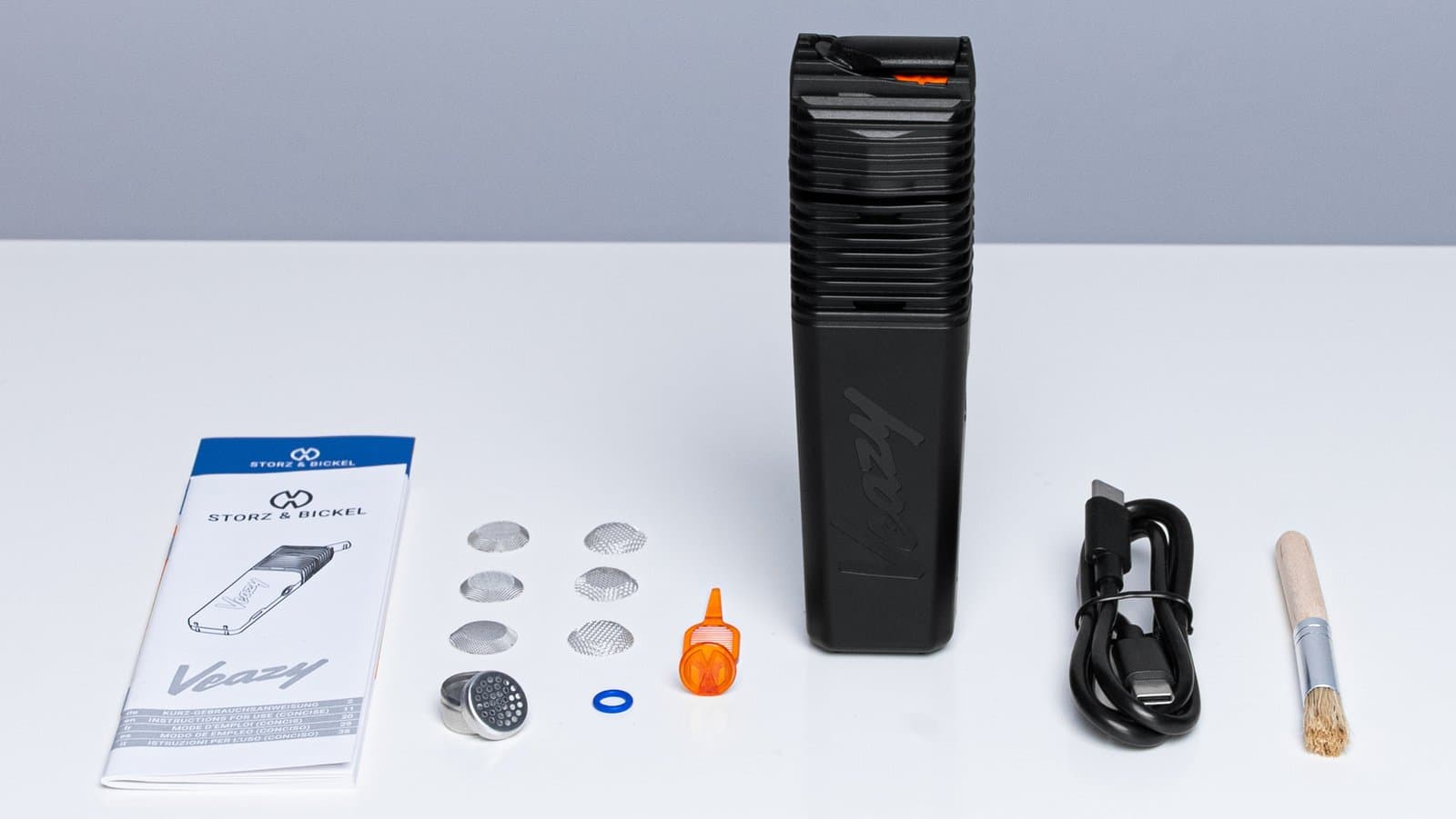 Schwarzes Veazy-Set als Flat Lay mit Sieben, Kapsel, Kabel, Bürste, Anleitung