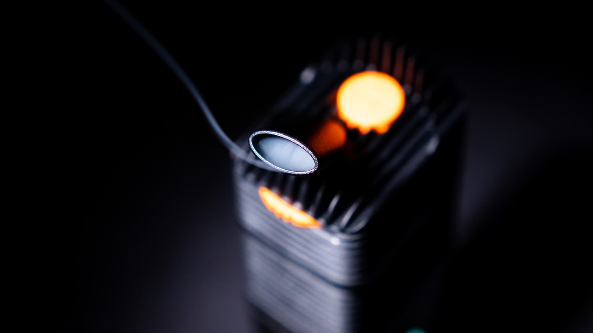 Moody macro photograph of a Venty vaporizer mouthpiece with the heater glowing orange in the background