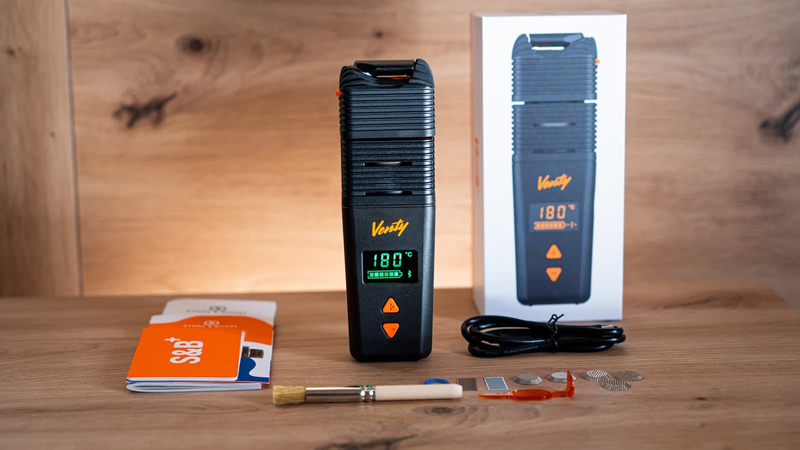 Venty mit grünem Display neben Verkaufsverpackung und Zubehör auf Holz