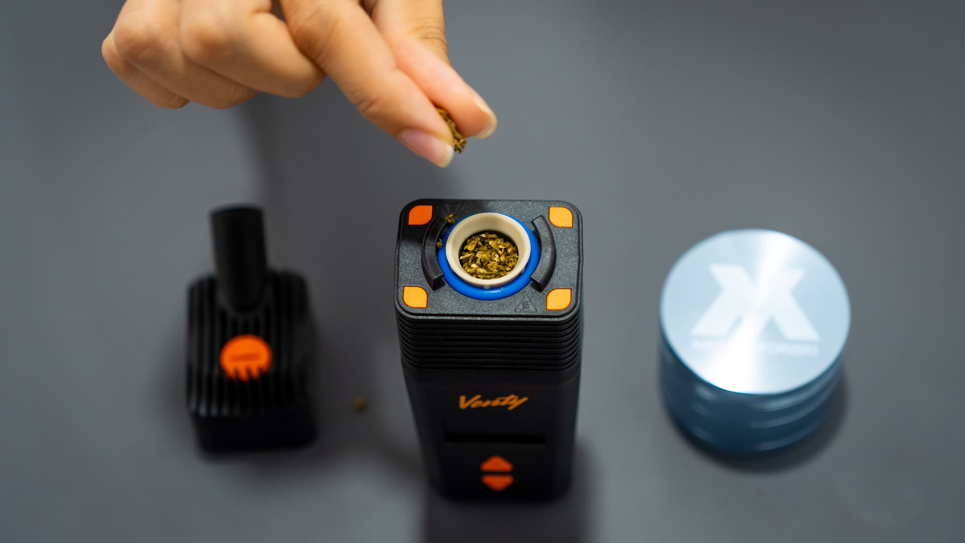 Hand befüllt die offene Heizkammer des Venty mit gemahlenem Cannabis, daneben ein Grinder