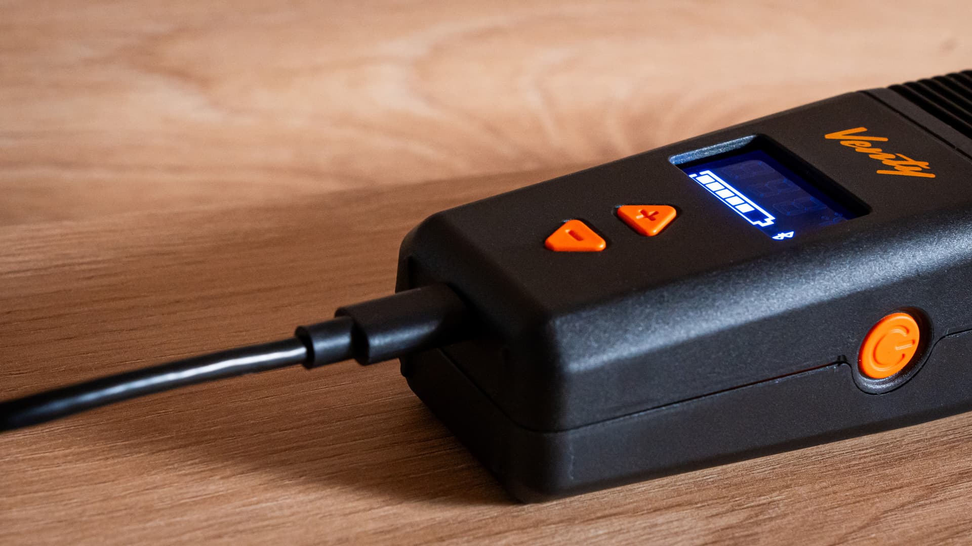 A USB-C cable plugged into the charging port of a Venty vaporizer with the battery indicator illuminated on its display