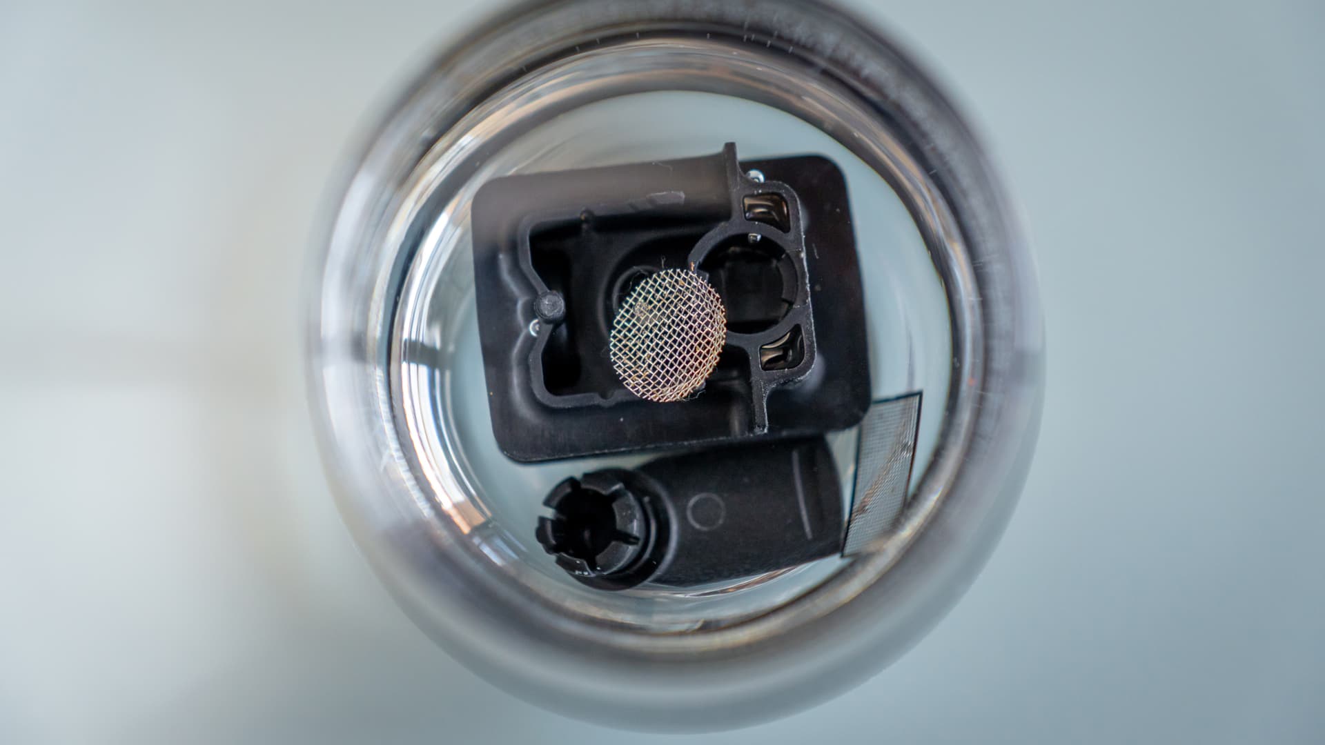 Venty cooling unit parts and screen soaking in a glass of alcohol, seen from above