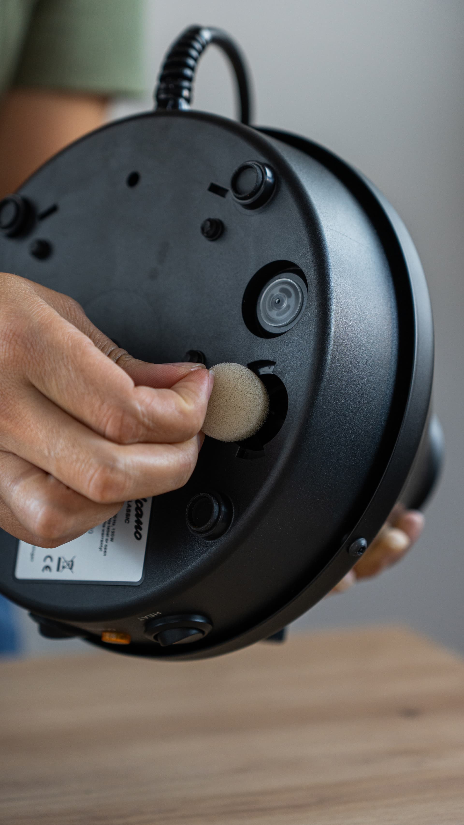 Hands removing replaceable air filter from bottom of Volcano Classic Onyx base