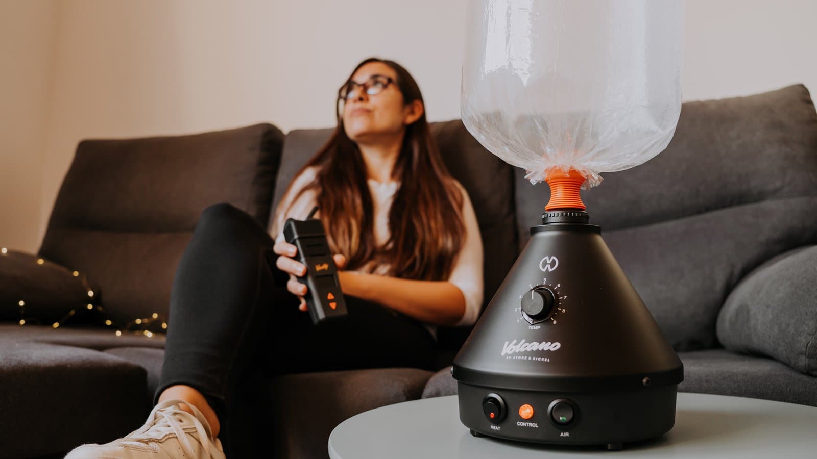 Woman on couch beside black Volcano with filled balloon